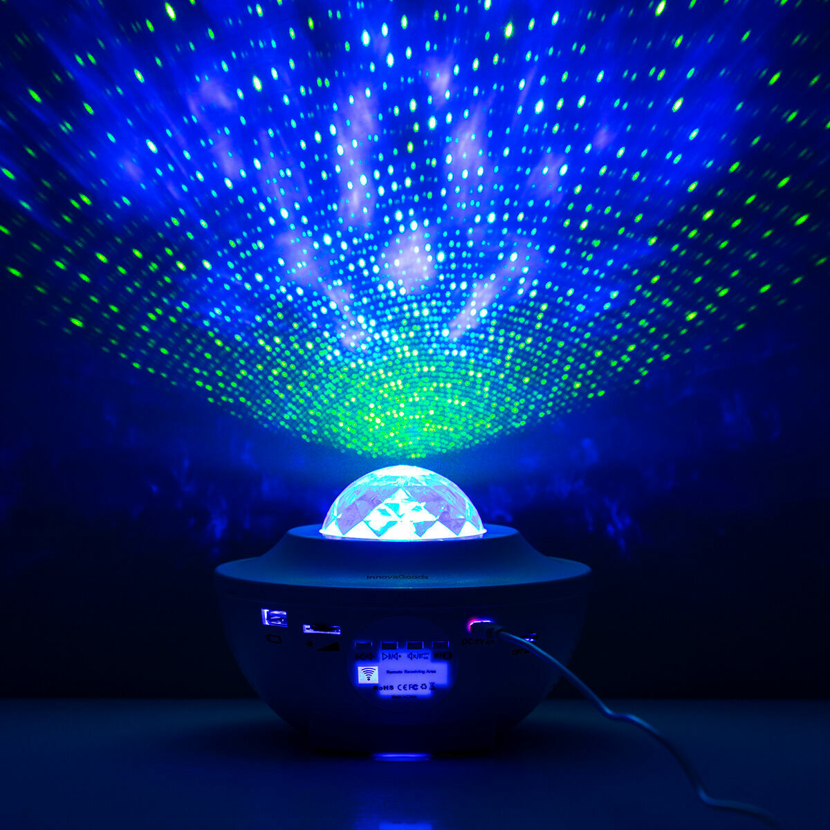 Ein leuchtender Galaxie-Projektor mit blauen und grünen Lichtern in dunkler Umgebung.