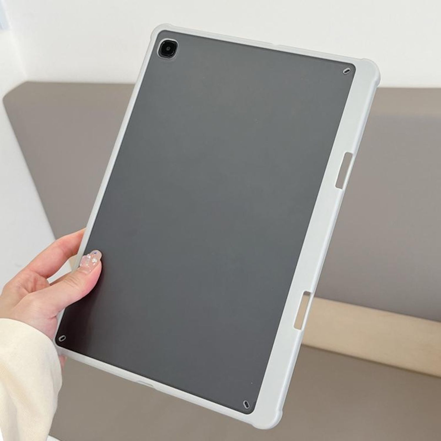 Una persona sostiene una funda de tableta. La funda es gris y blanca.