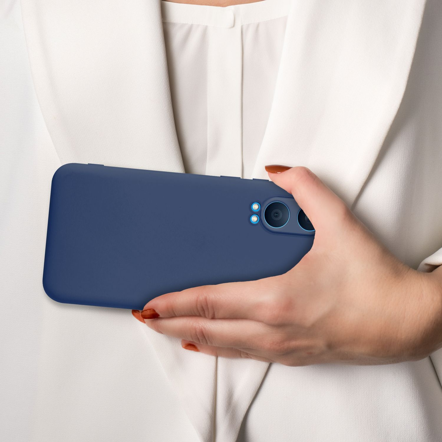Eine Person hält eine blaue Handyhülle vor ihrem weißen Hemd.