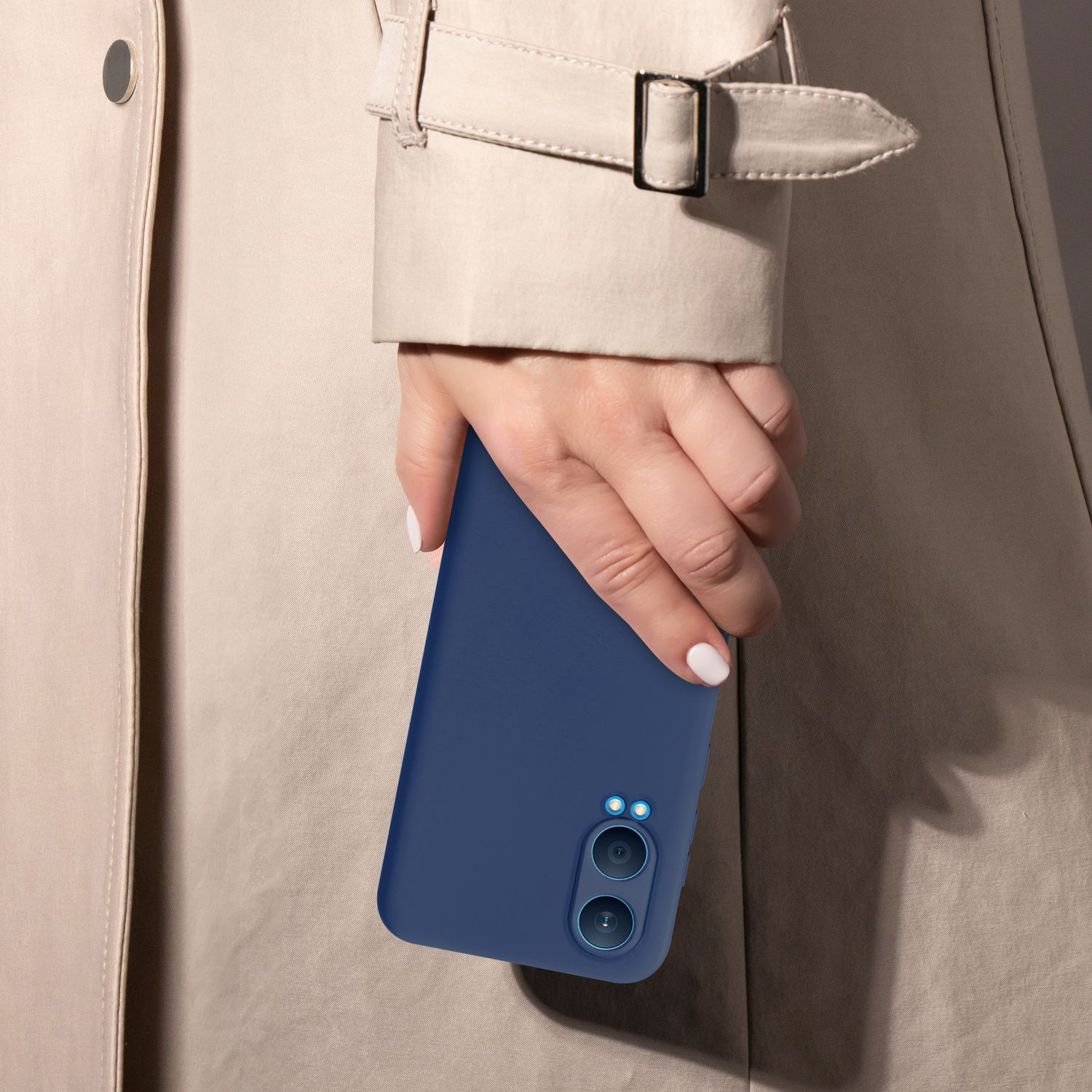 Eine Person, die eine blaue Handyhülle vor einem beigefarbenen Mantel hält.