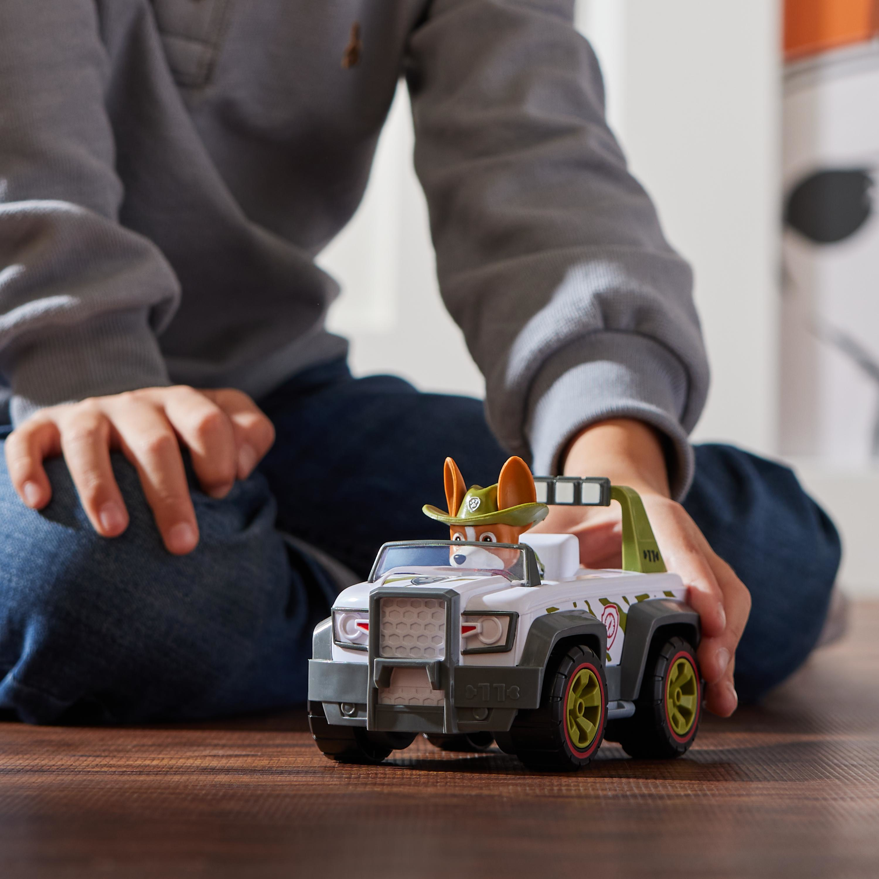 Dziecko bawi się pojazdem zabawką. Zabawka to biało-zielony jeep z kierowcą z kreskówek.