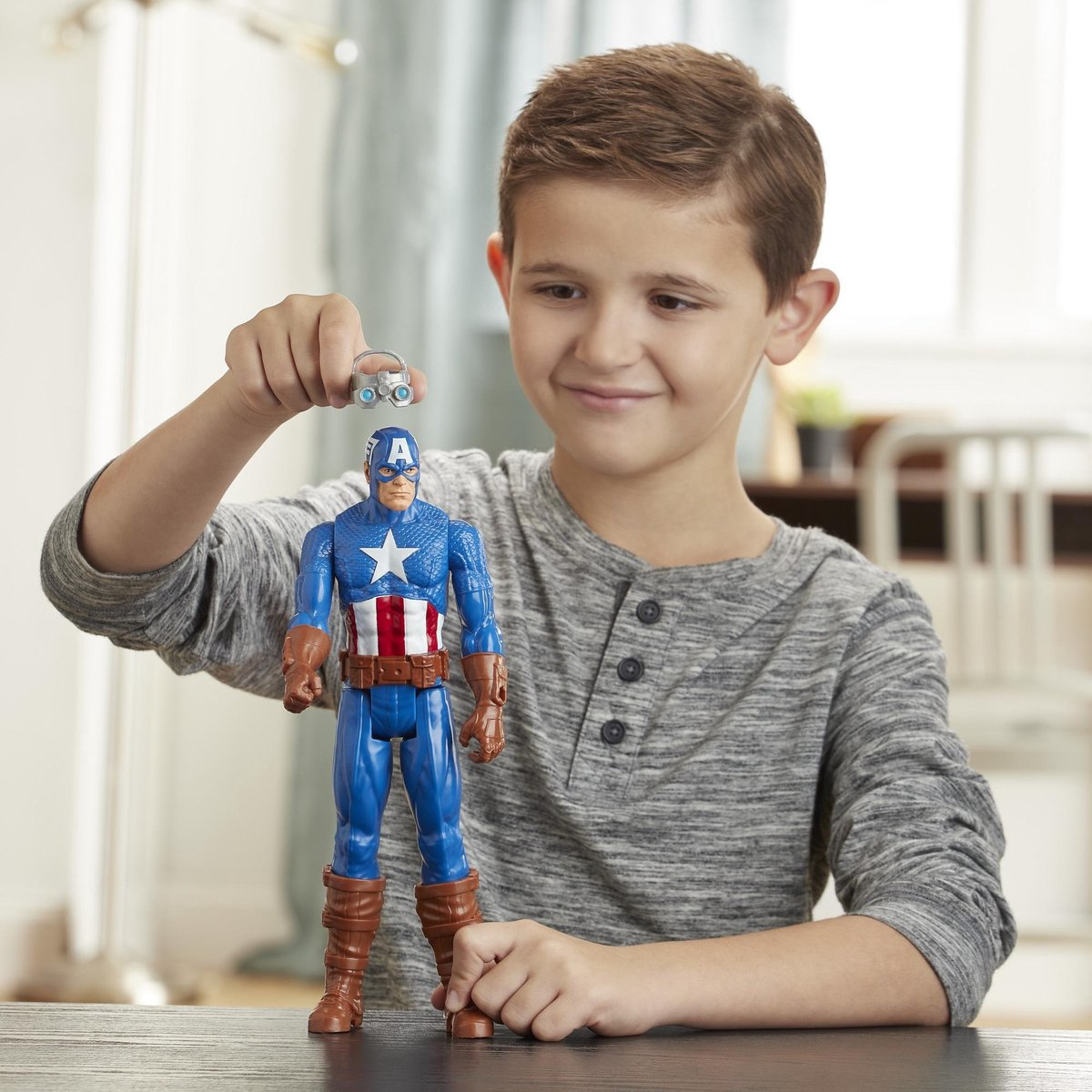 Un ragazzino tiene in mano un personaggio d'azione di Captain America e una macchinina. Sorride.