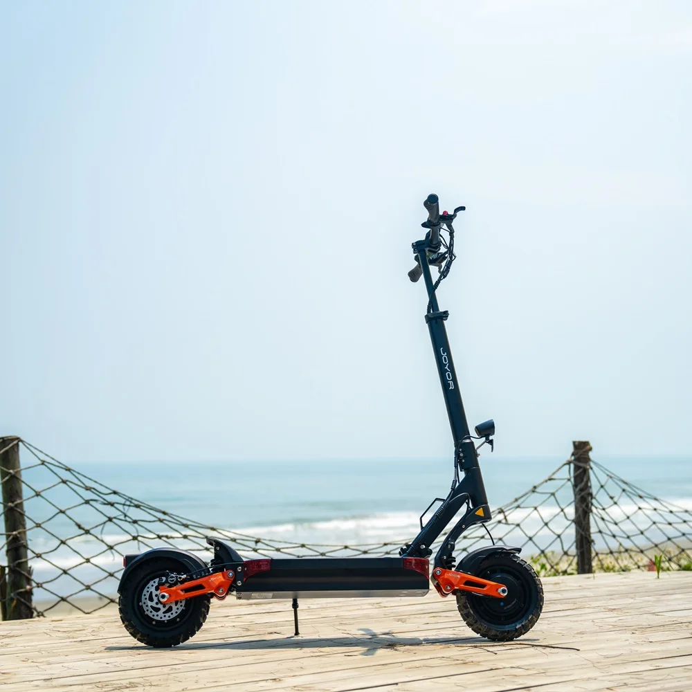 Scooter elettrico nero su un ponte di legno, con vista sull'oceano. Il cielo è blu.