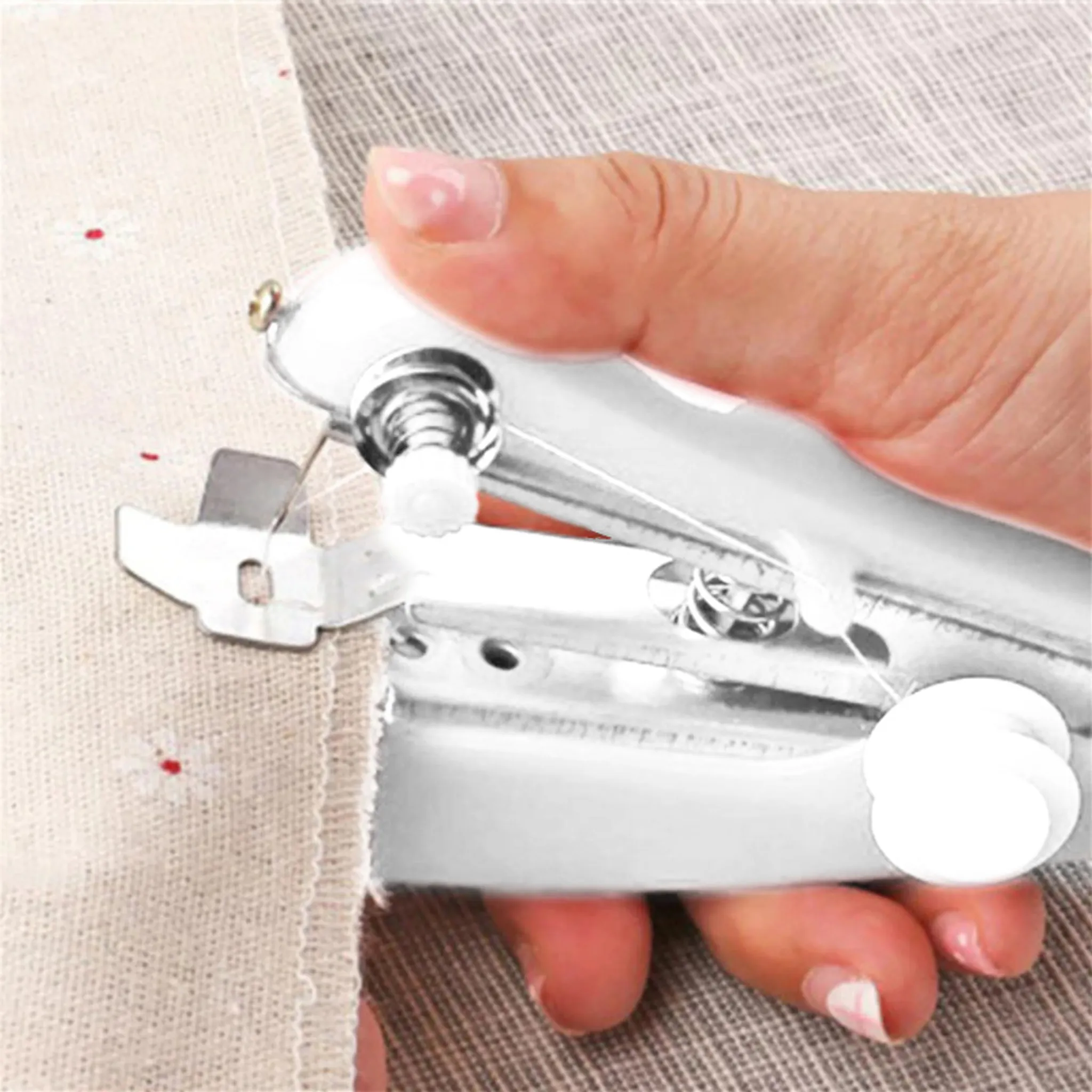 Eine weiße Handnähmaschine näht Stoff. Eine Hand bedient das Gerät.