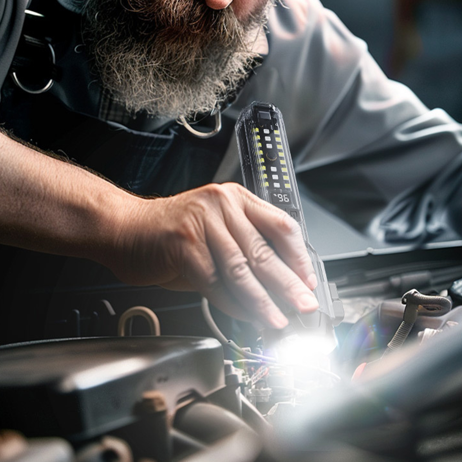 Ein Mechaniker, der mit einer Taschenlampe den Motorraum eines Autos inspiziert, der mit hellem Licht beleuchtet wird.