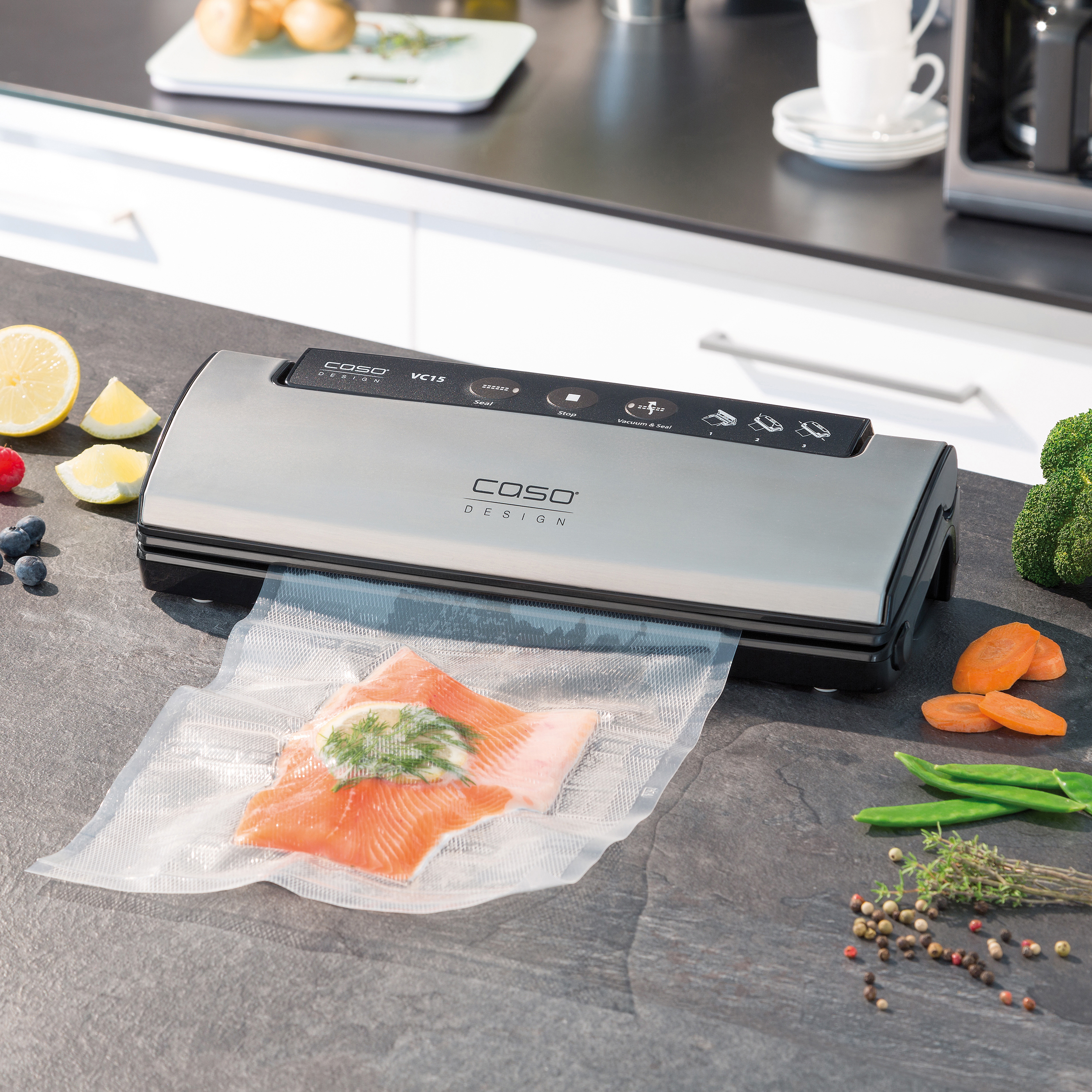 Vakuumiergerät mit Essen in einem Beutel. Es gibt Gemüse und Zitronenscheiben um die Maschine herum.