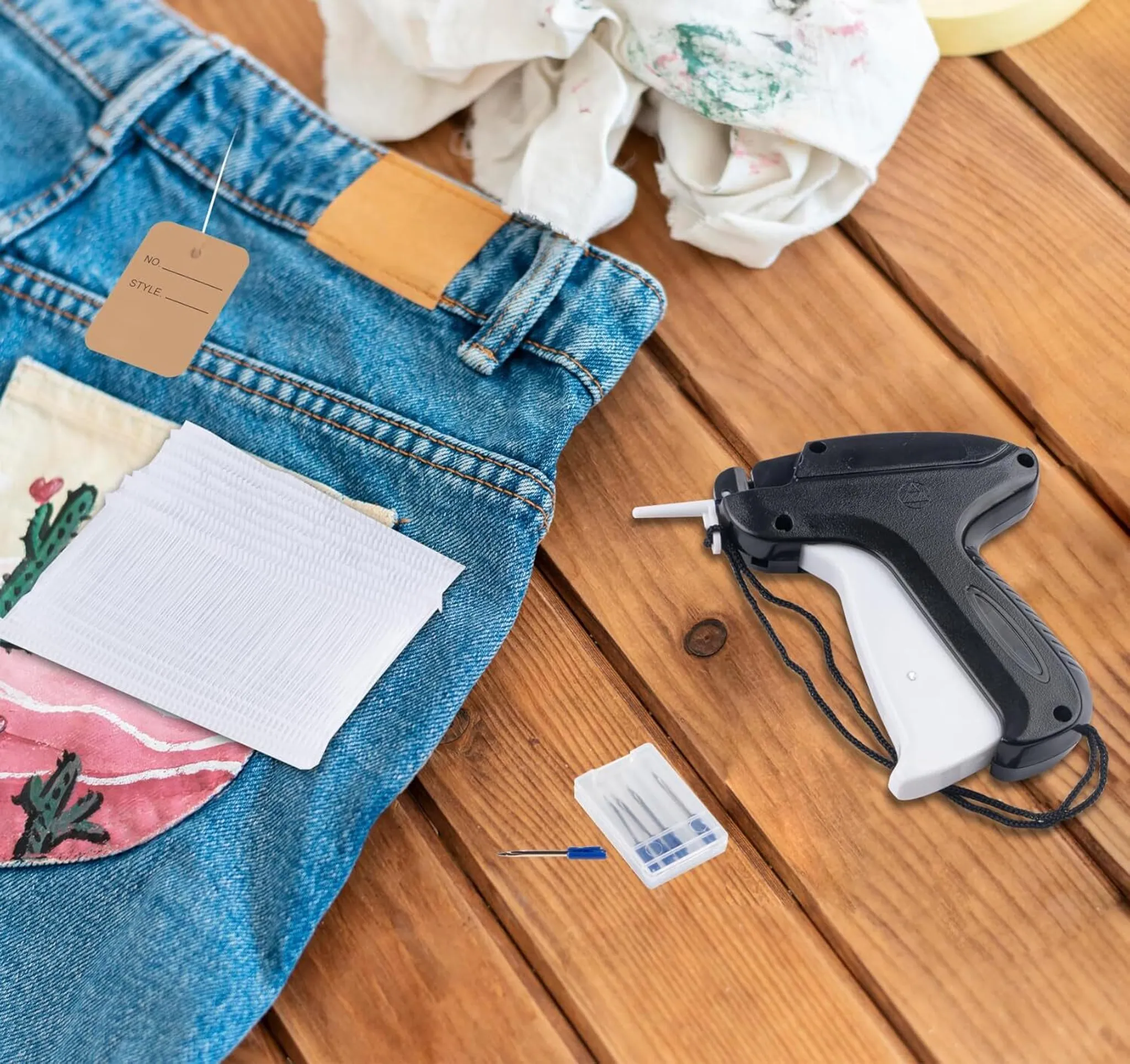 Jeans mit Etikett, weißen Etikettenblättern und einer Etikettierpistole auf einer Holzoberfläche.
