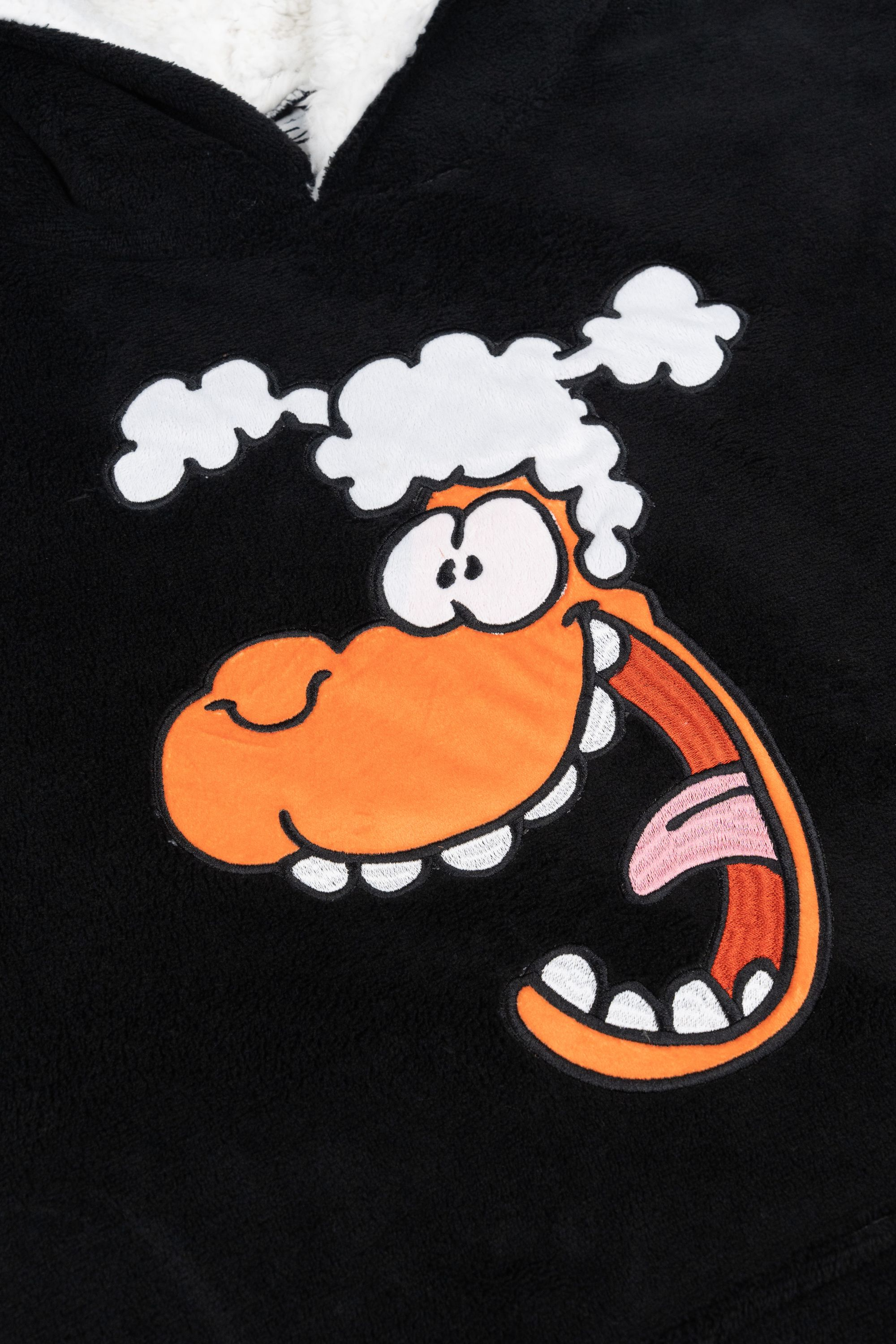 Nahaufnahme eines schwarzen Hoodies mit einem Cartoon-Schafgesicht und den Worten 'GEILE SCHEISSE: KUSCHELN!'.