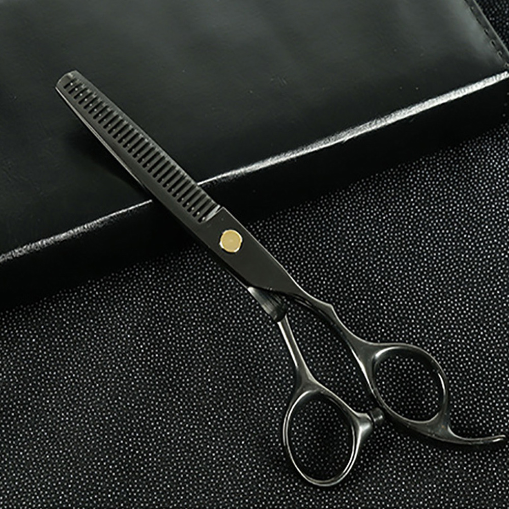 Schwarze Friseur-Effilierschere mit Goldschraube, liegt auf schwarzer Oberfläche.