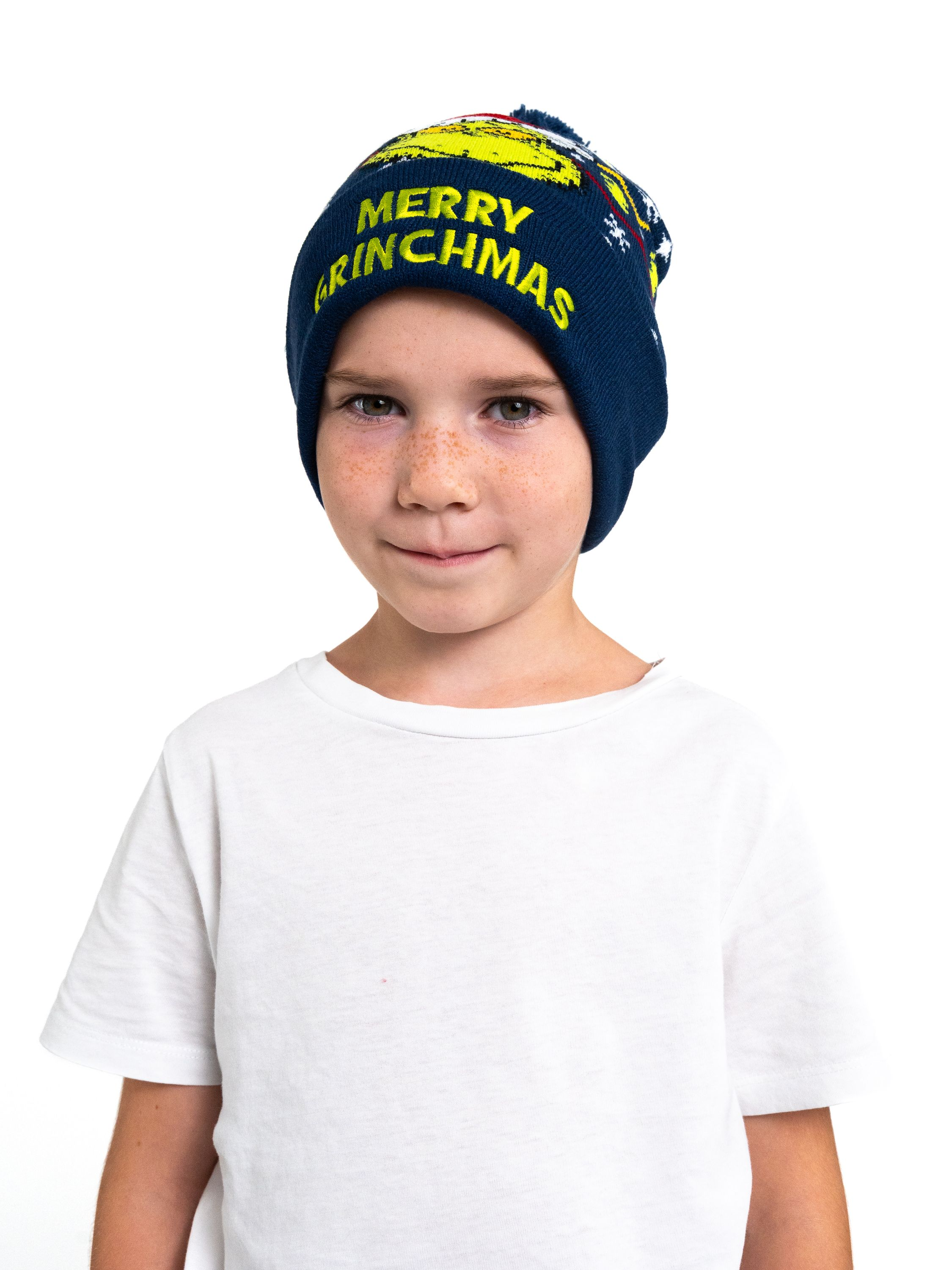 Ein Junge mit einer marineblauen Mütze mit den Worten „Merry Grinchmas“. Er lächelt in die Kamera.