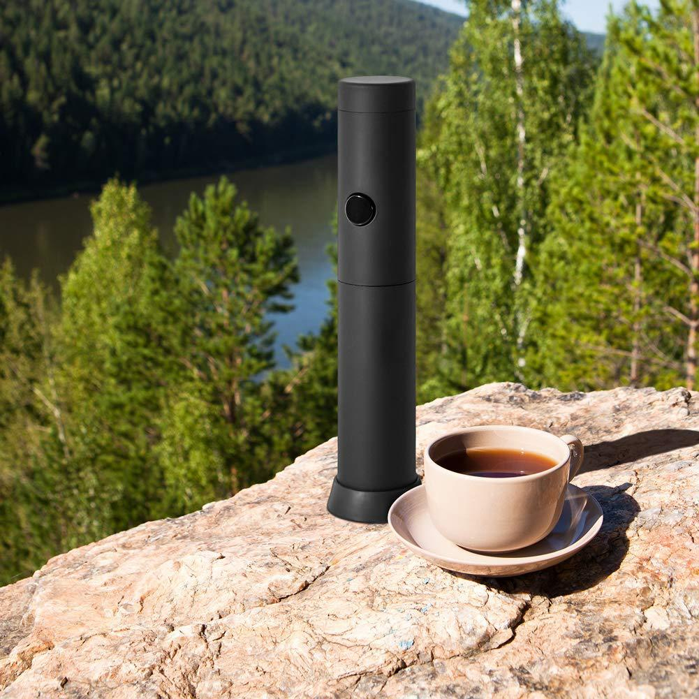 Schwarzer Milchaufschäumer und Tasse Tee auf Felsen. Hintergrund aus Bäumen und See.