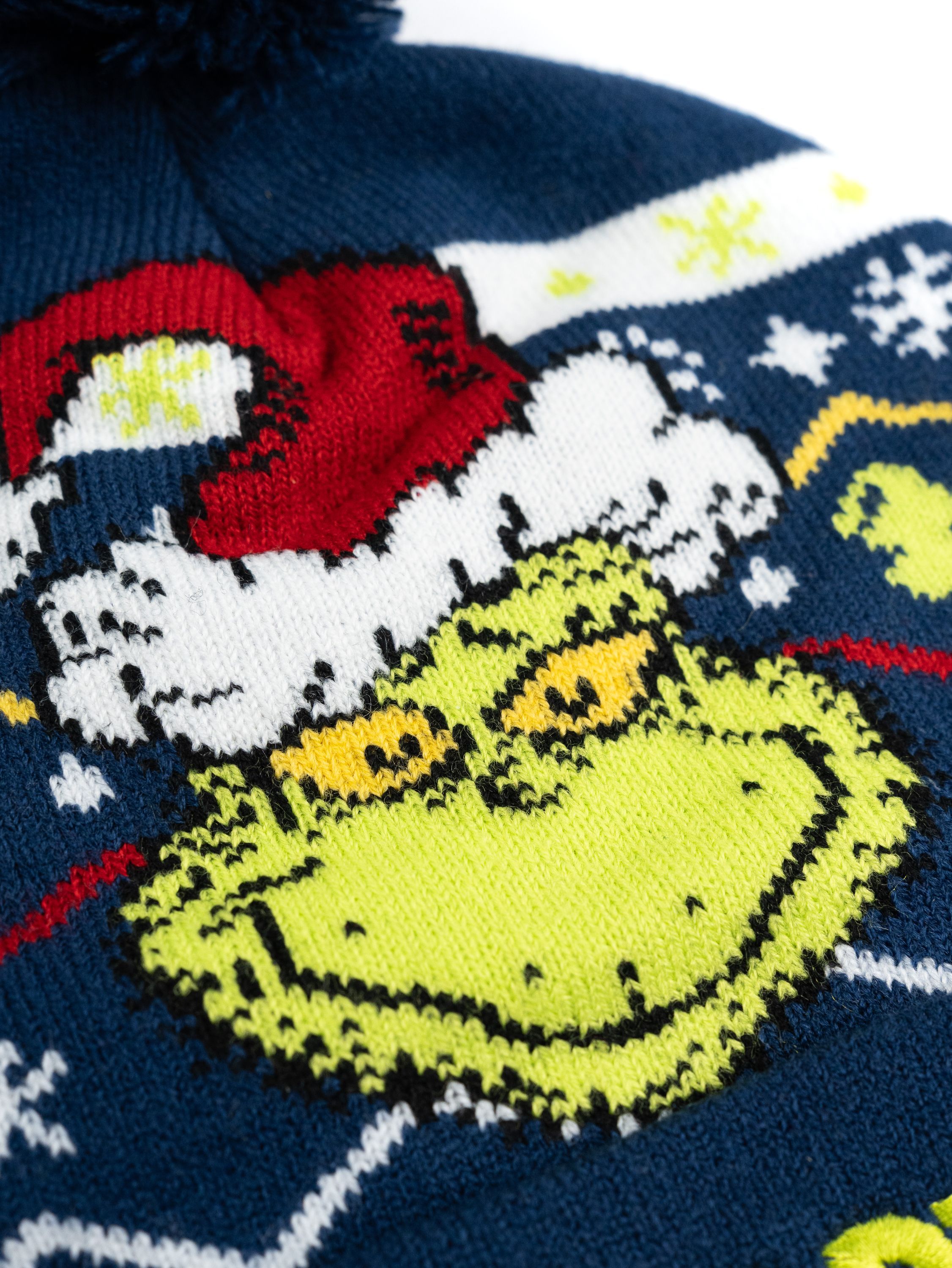 Nahaufnahme einer Strickmütze mit Grinch-Motiv. Dunkelblau mit Grinch-Gesicht und Weihnachtsmütze.
