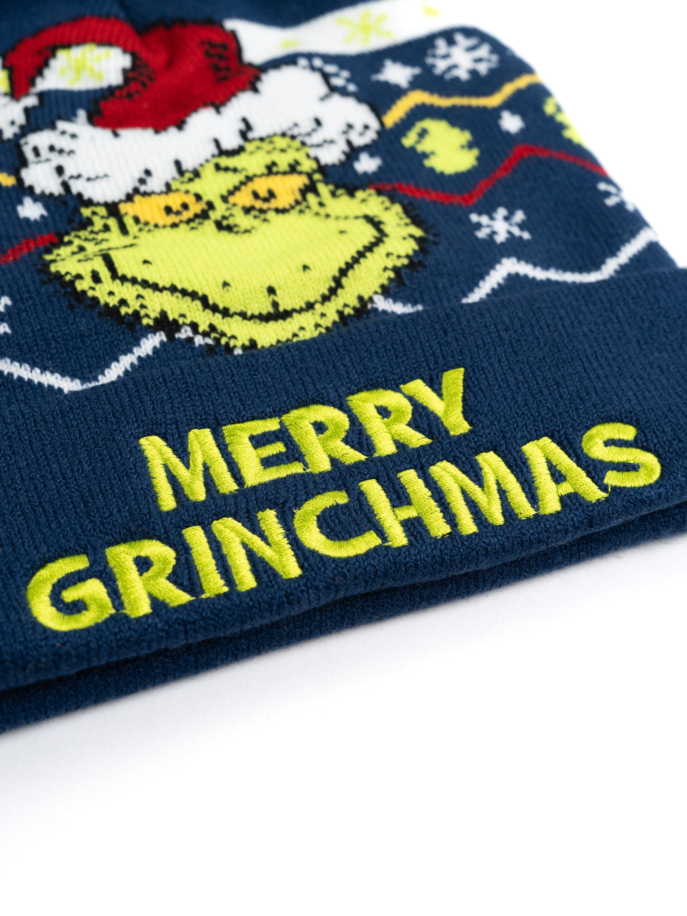 Eine marineblaue Mütze mit dem Grinch-Cartoon-Charakter und gelbem Text 'Merry Grinchmas'.