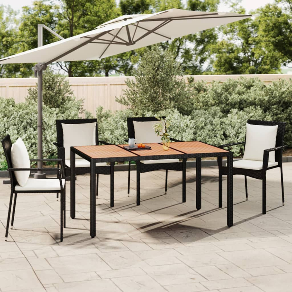 Garten-Terrassenset mit Tisch, Stühlen und Sonnenschirm. Grüne Büsche im Hintergrund.