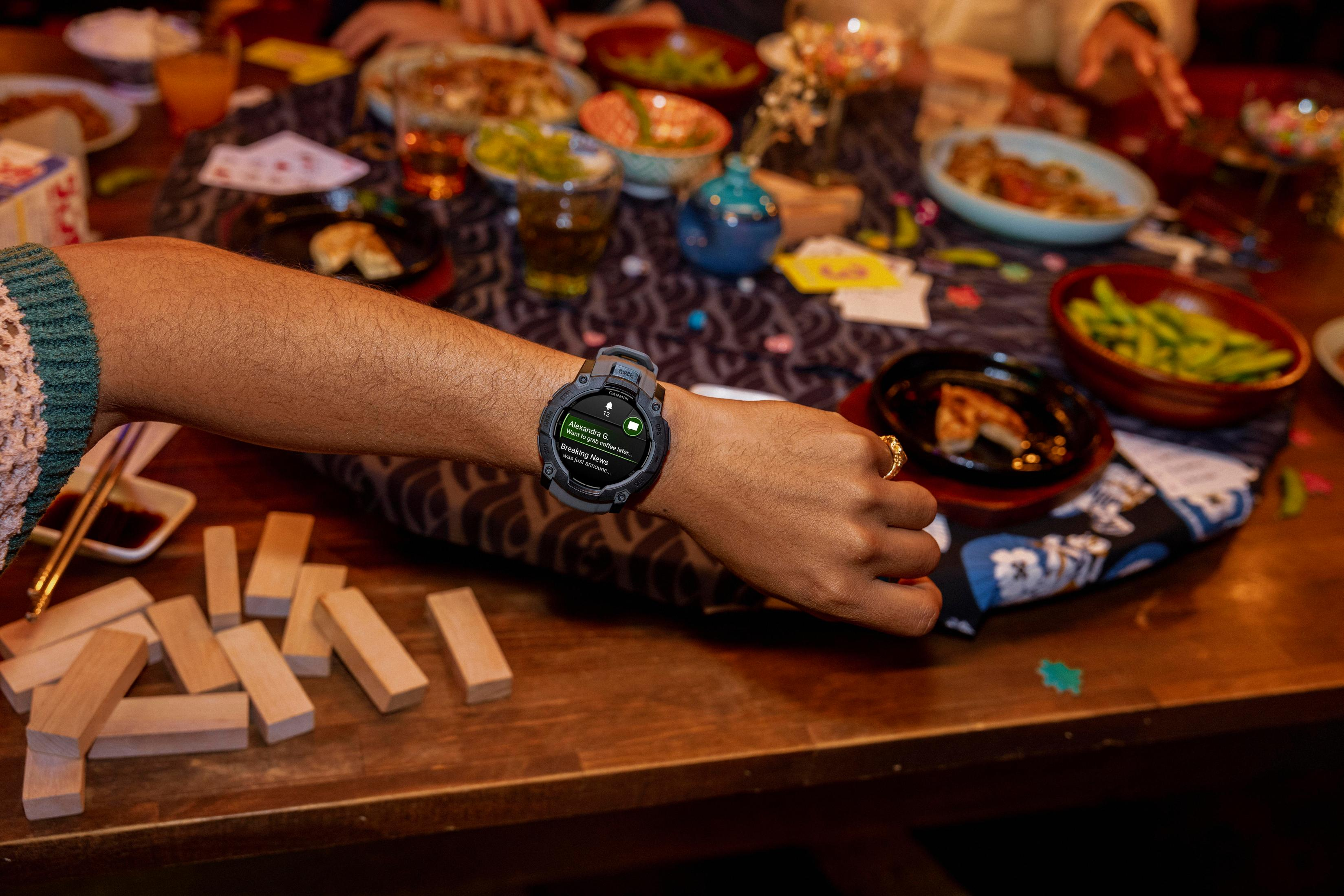 Persoon die een smartwatch draagt aan een tafel met eten.