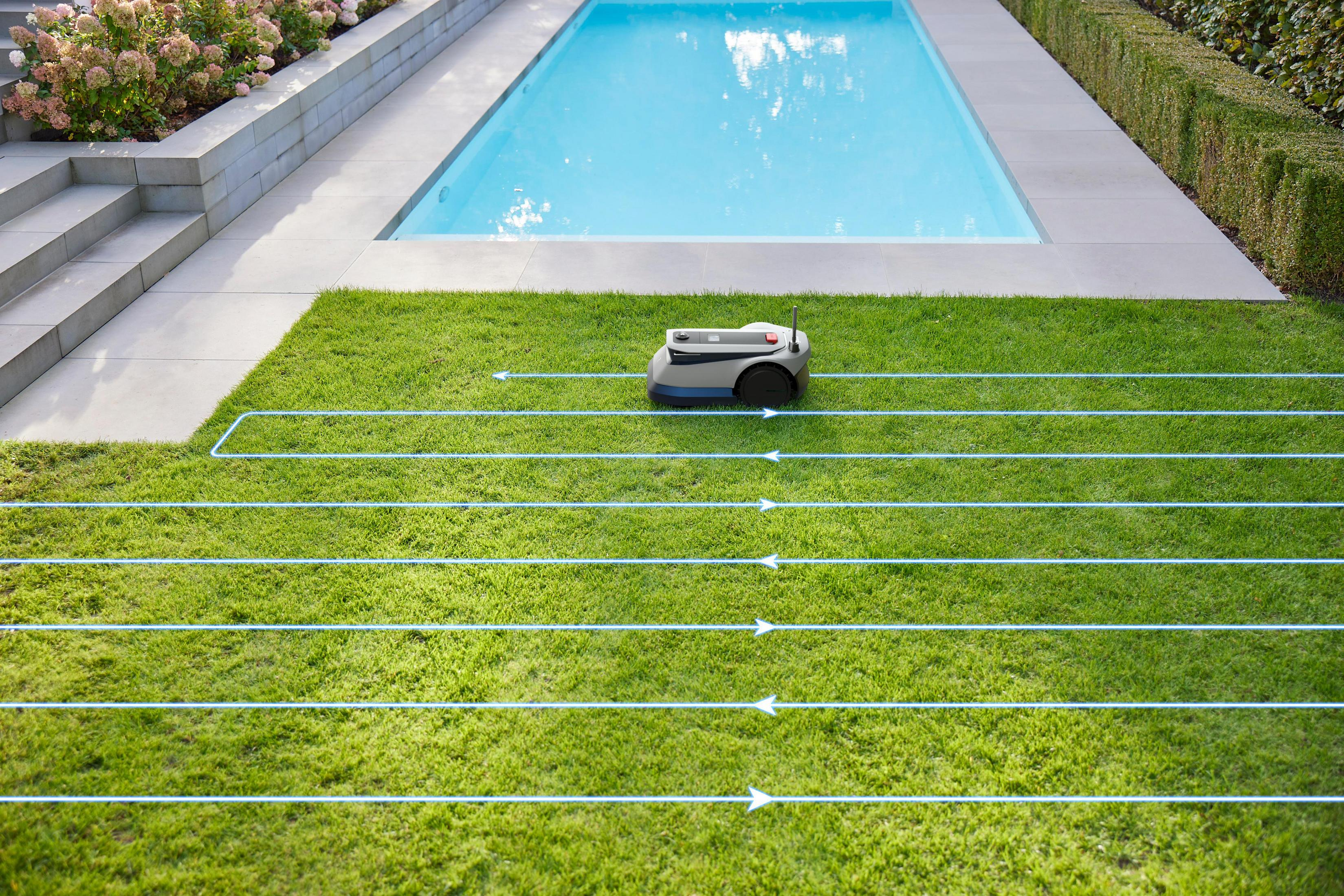 Ein Roboter-Rasenmäher auf grünem Gras mit Mähpfaden. Ein Pool ist im Hintergrund.