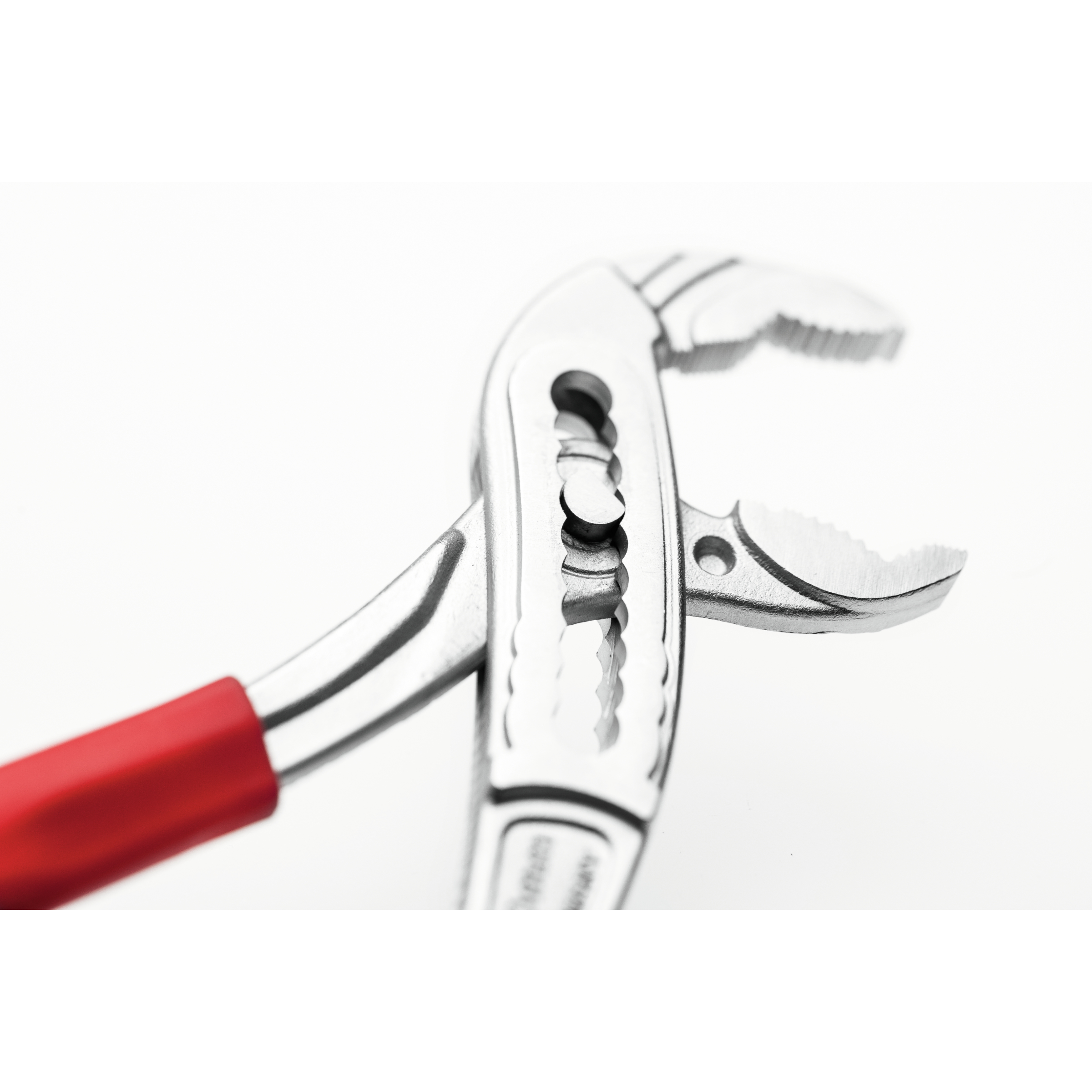 Zbliżenie metalowego klucza nastawnego z czerwonym uchwytem na białym tle.