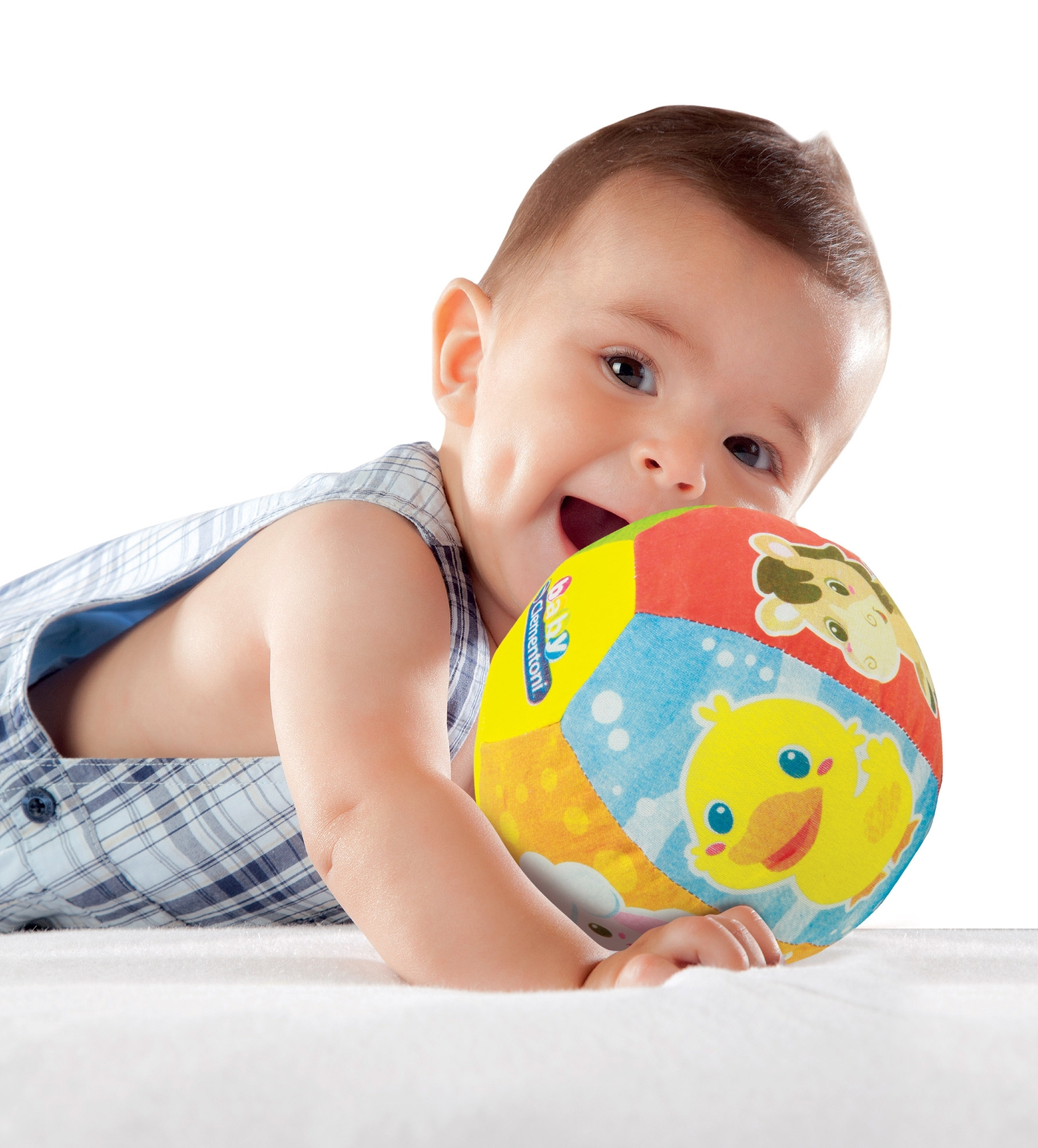 Lachendes Baby auf weißem Laken, spielt mit buntem Ball.