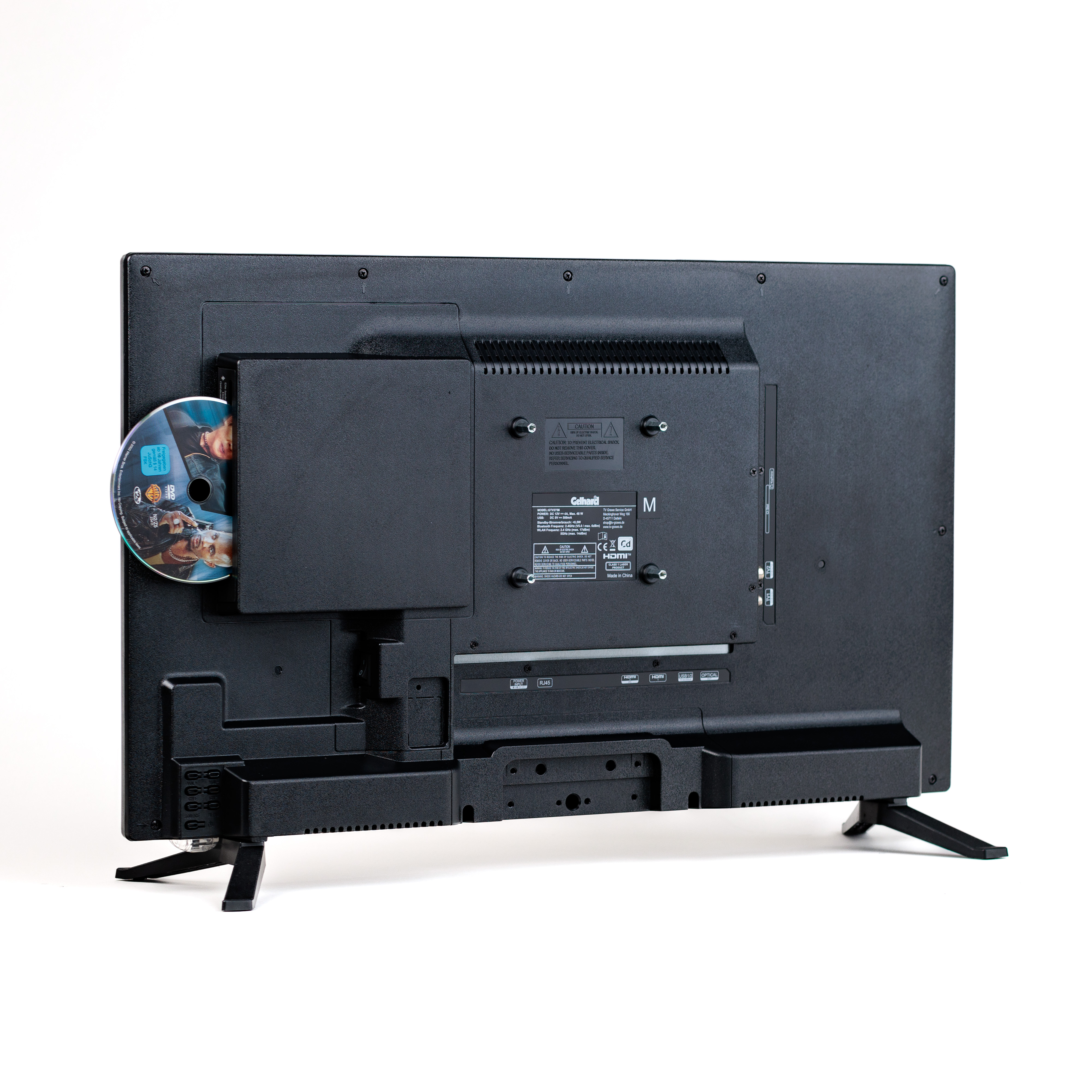 Die Rückseite eines schwarzen Fernsehers mit eingelegter DVD. Der Fernseher steht auf einem Ständer vor weißem Hintergrund.