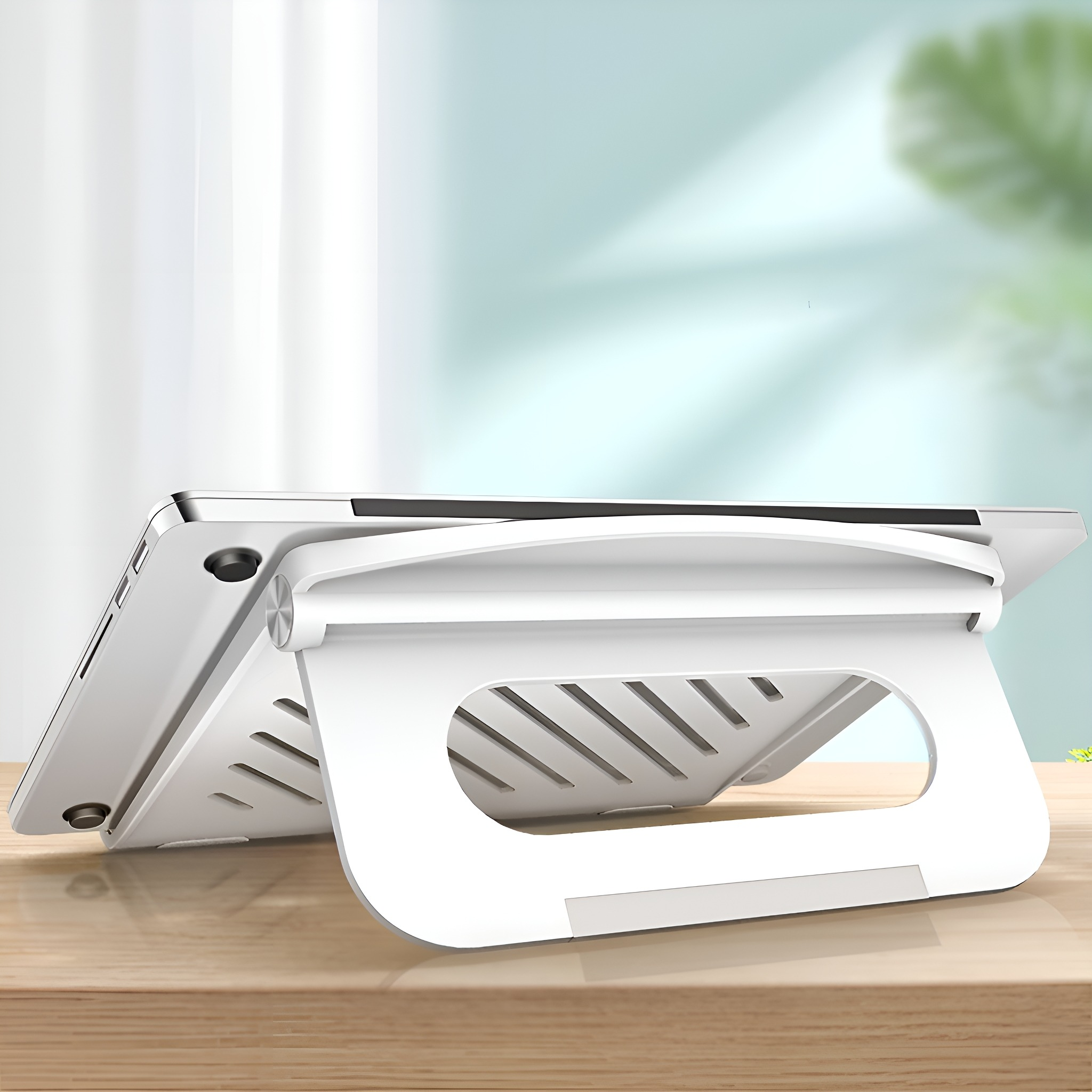 Ein weißer Laptop-Ständer auf einem Holztisch, der einen Laptop trägt, mit einem Fenster im Hintergrund.