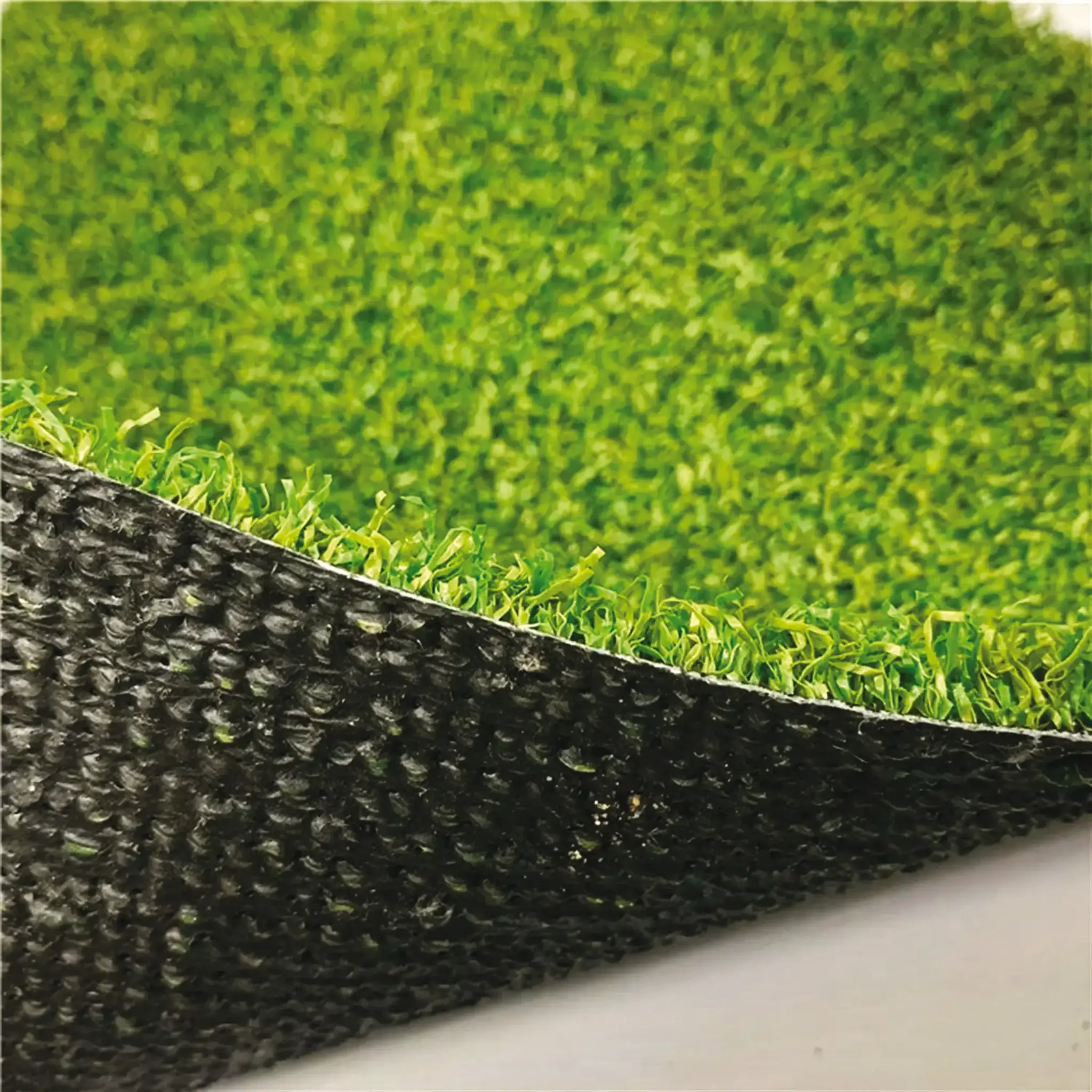 L'image montre une surface d'herbe artificielle verte avec une base noire.