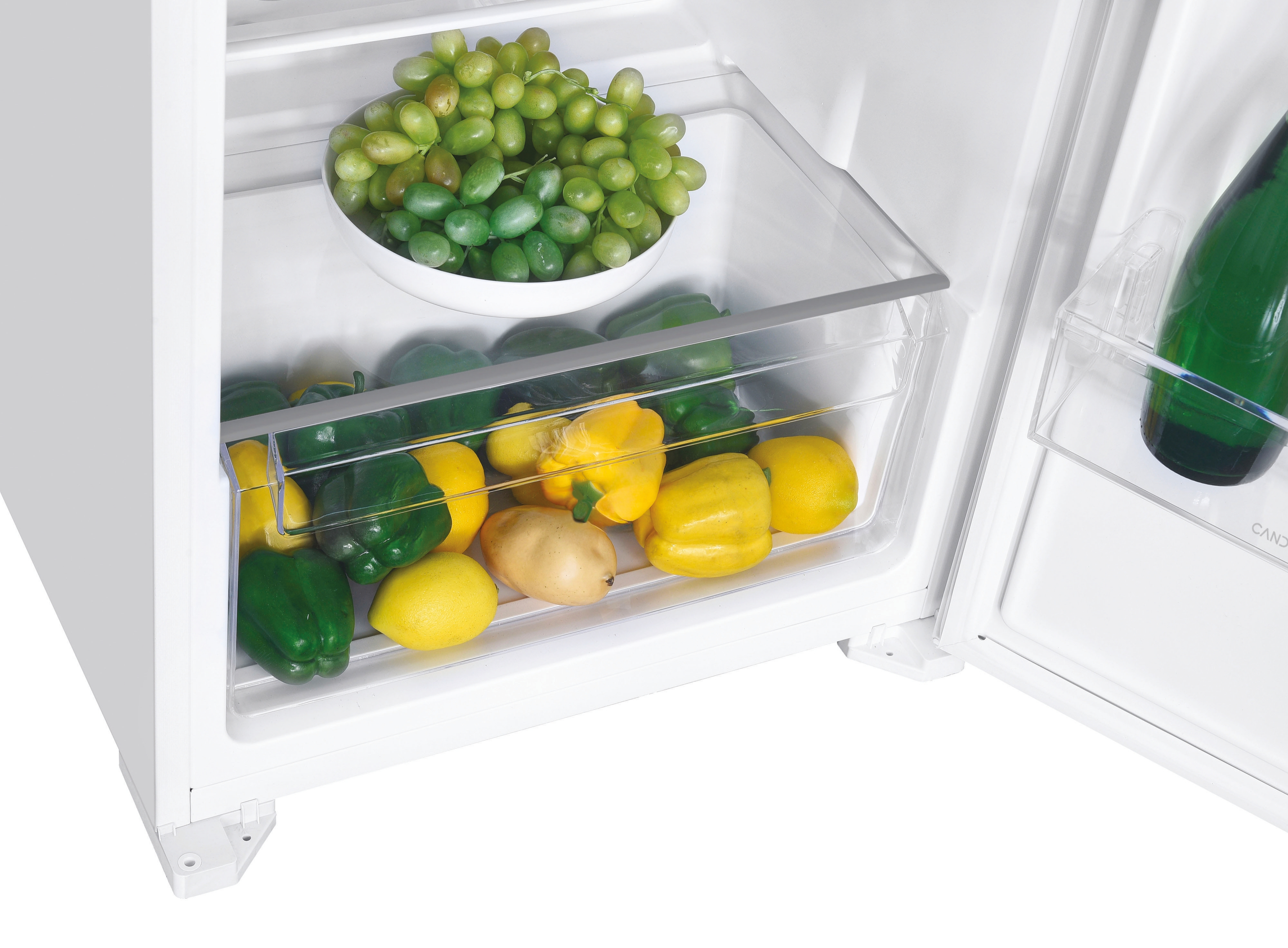 All'interno di un frigorifero bianco con un cassetto che contiene peperoni, limoni e uva.