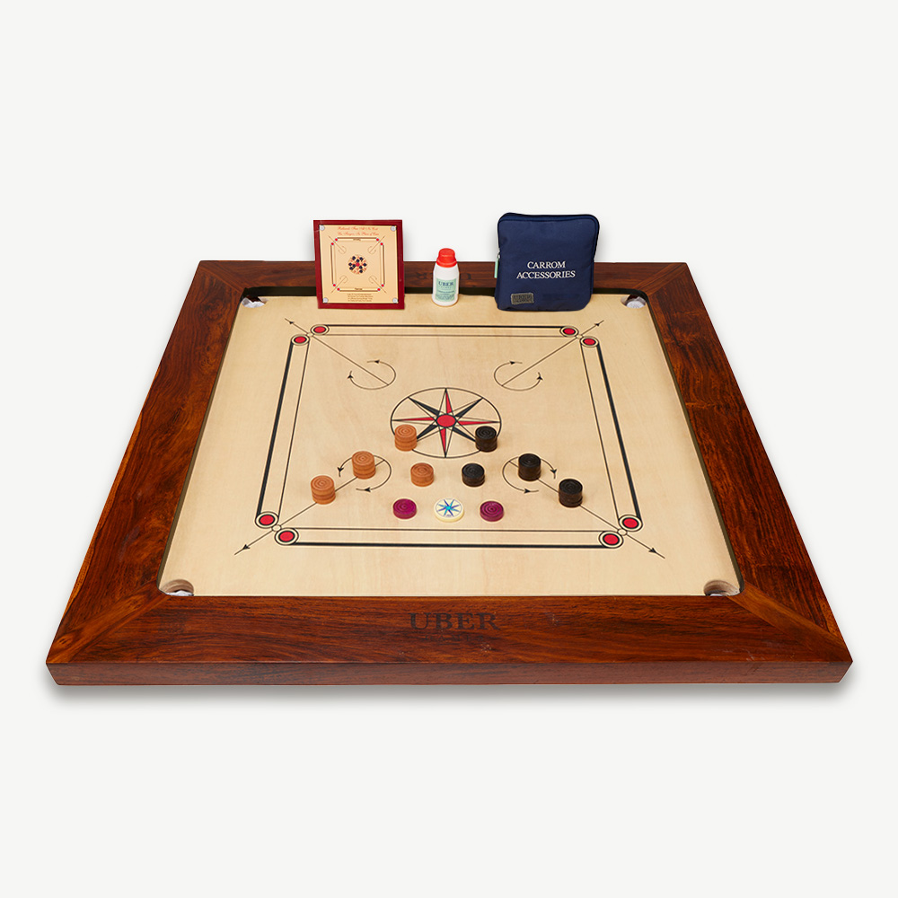 Carrom-Brett mit Steinen, Pulver und Zubehör. Dunkler Holzrahmen, beige Oberfläche.