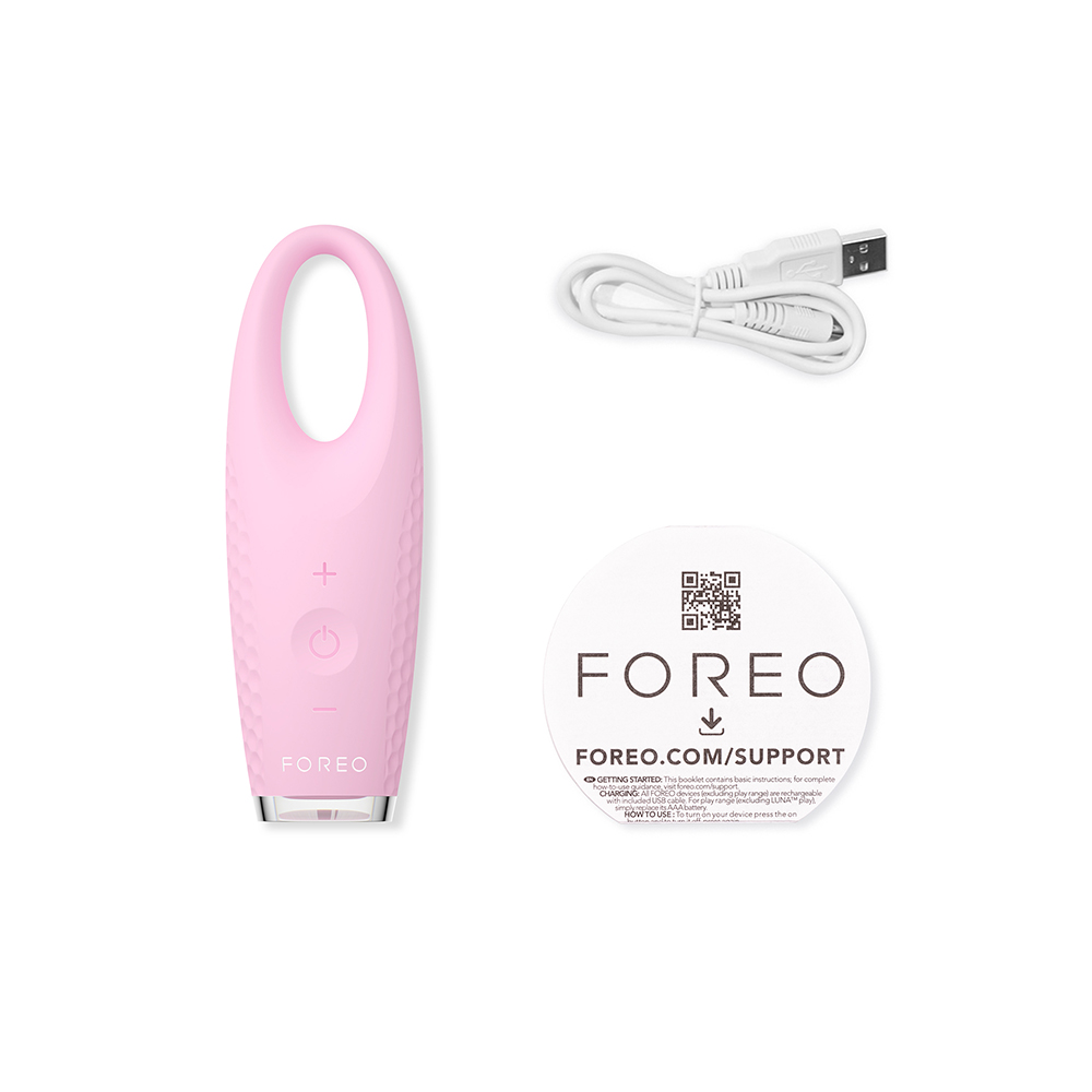 Roze gezichtsreinigingsapparaat met een kabel en een boekje. FOREO-tekst en logo. Witte achtergrond.
