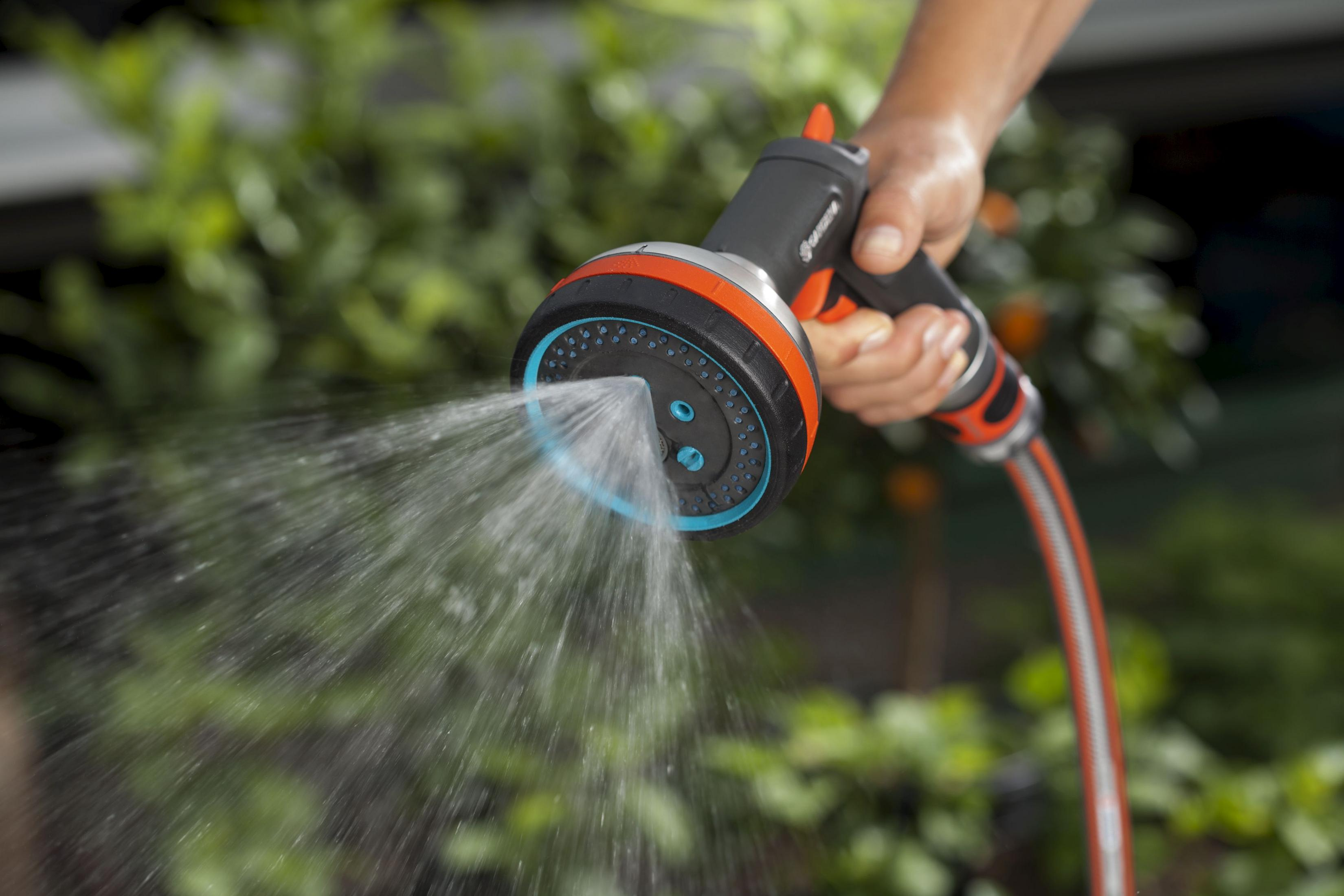 Pistola a spruzzo Gardena che spruzza acqua, con sfondo verde e dettagli arancioni.