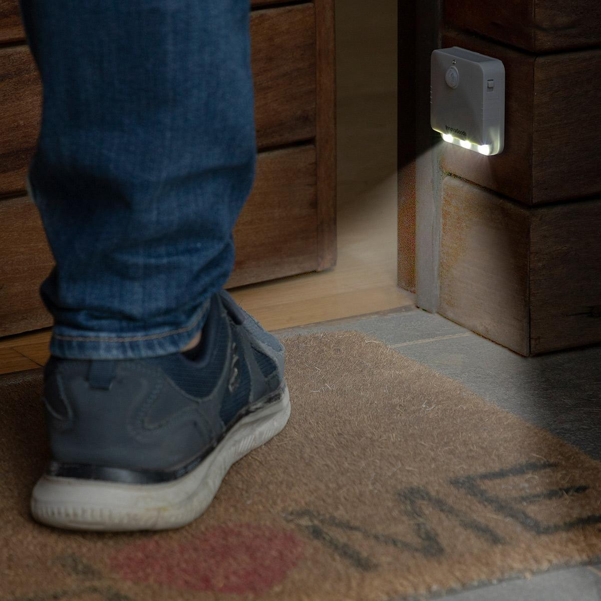 Le gambe e le scarpe di una persona vicino a una porta con una luce a parete illuminata.