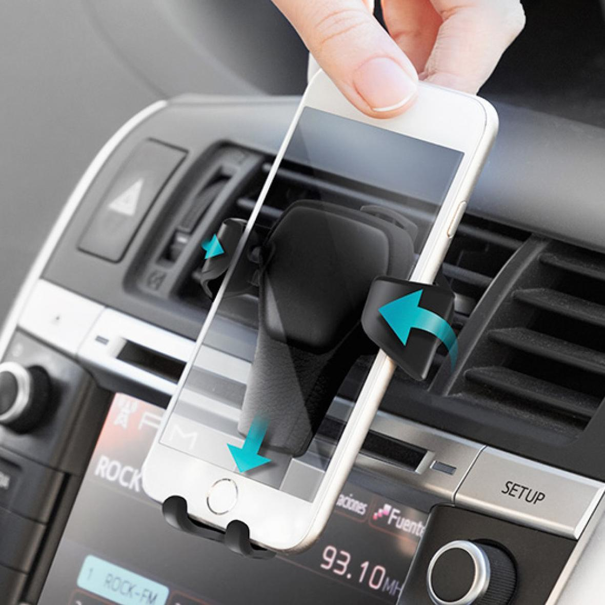 Una mano tiene un telefono bianco in un'auto, montato sul cruscotto.