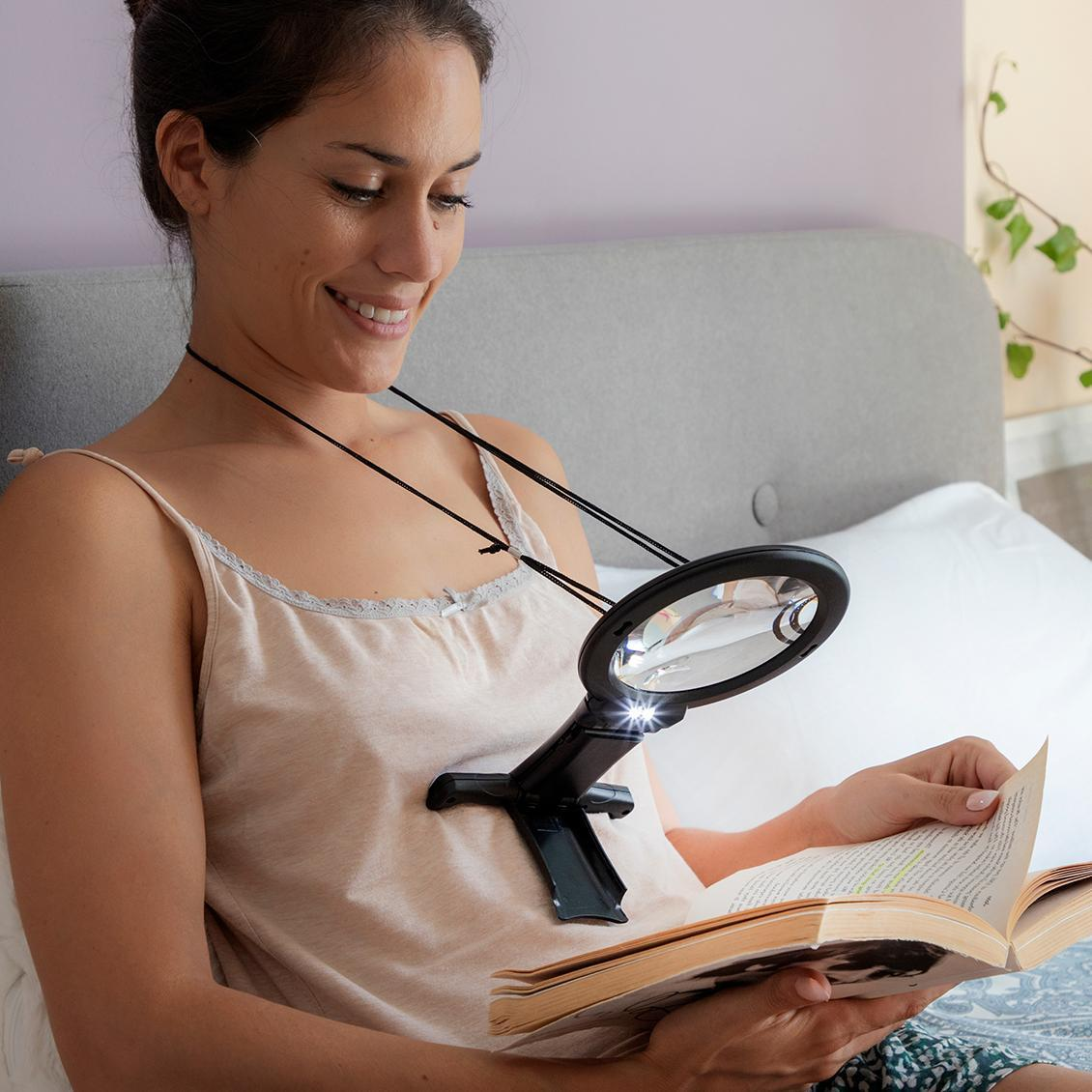 Mujer usando un magnificador de cuello, leyendo un libro en la cama.