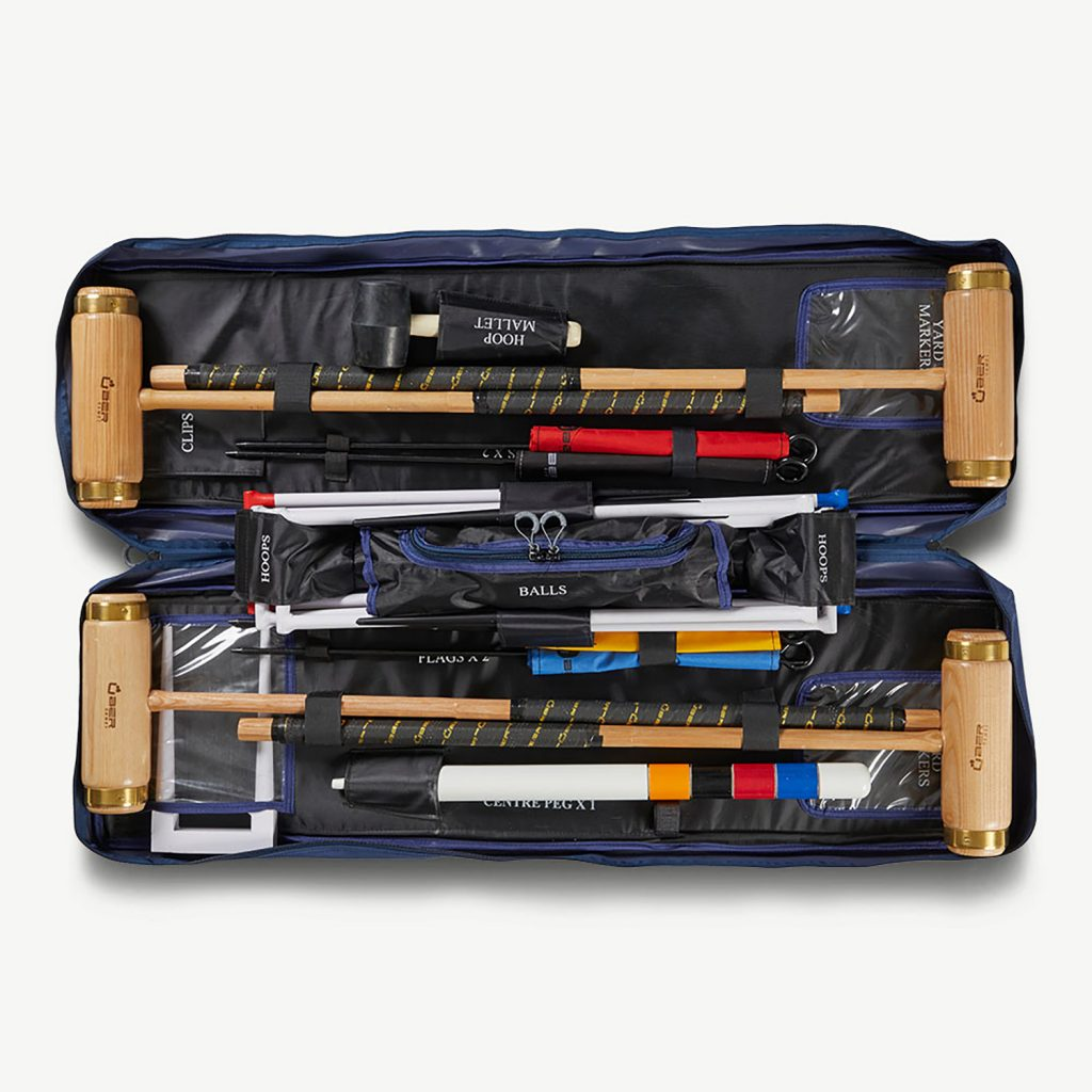 Ein Krocket-Set mit Schlägeln, Reifen, Bällen und Fahnen wird in einer blauen Tragetasche ausgestellt.