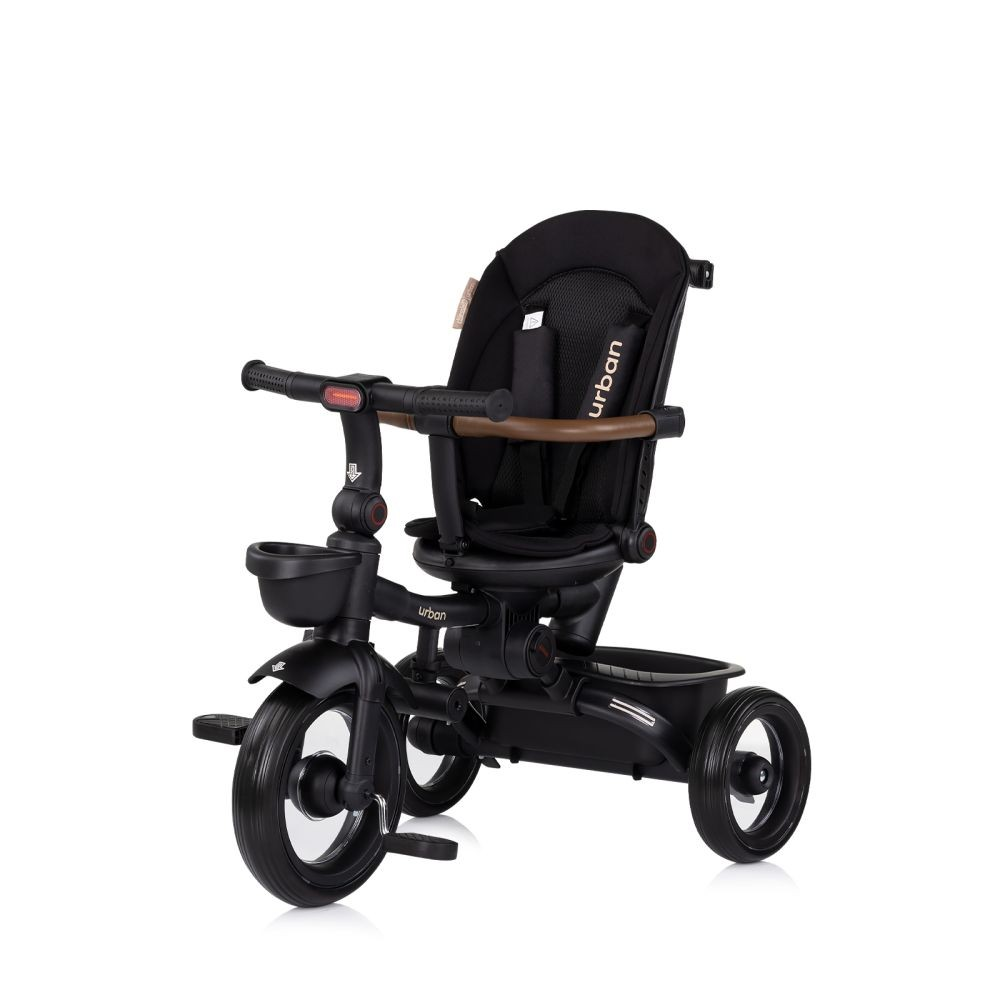 Triciclo para bebé negro con manija marrón y asiento negro. Tiene una cesta y está sobre un fondo blanco.