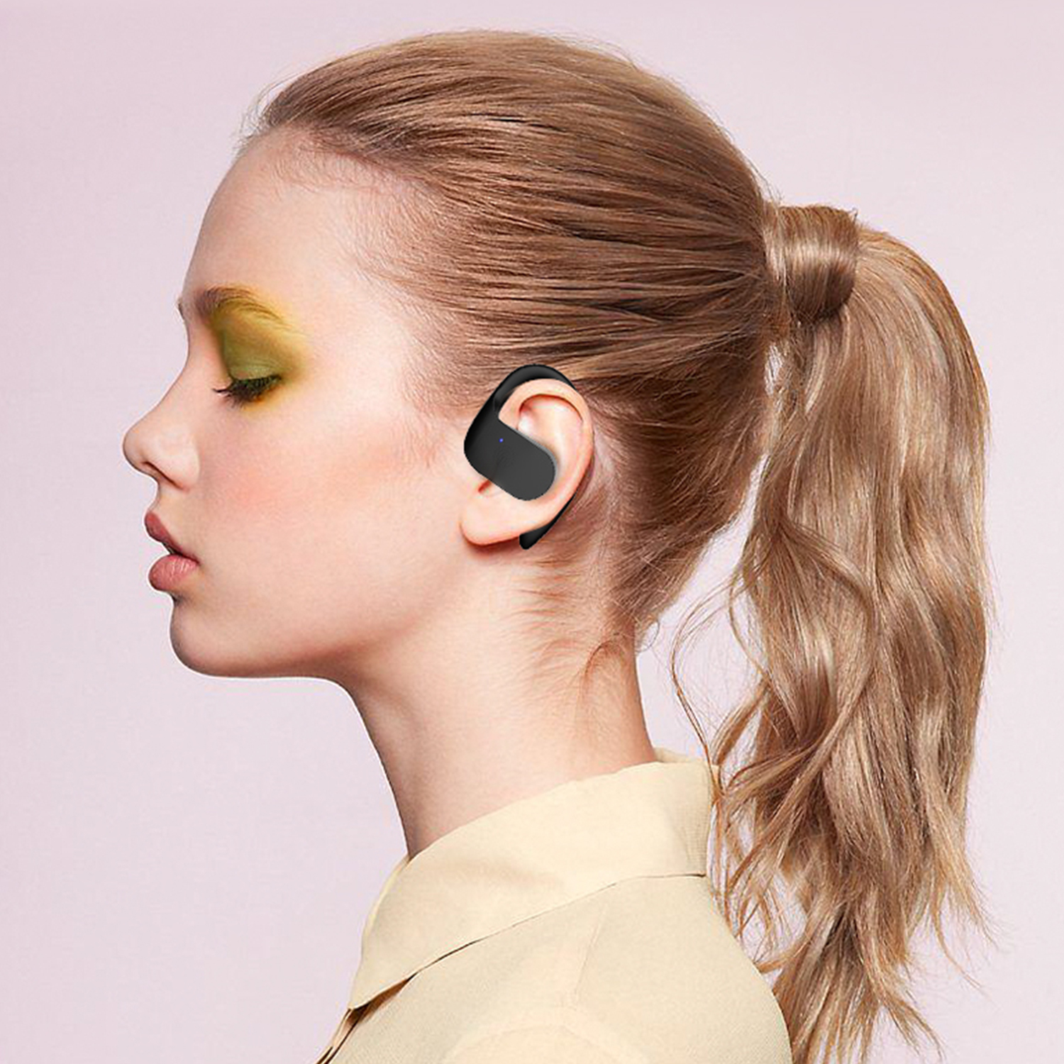 Donna con auricolare nero. Ha una coda di cavallo e guarda a sinistra. Sfondo rosa.