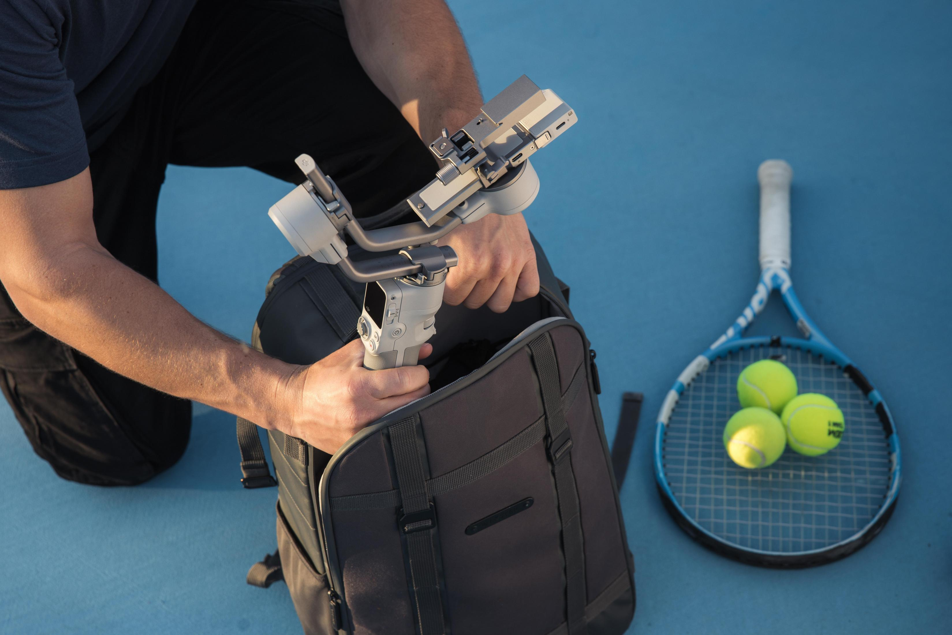 Eine Person legt einen Telefonstabilisator in einen Rucksack.