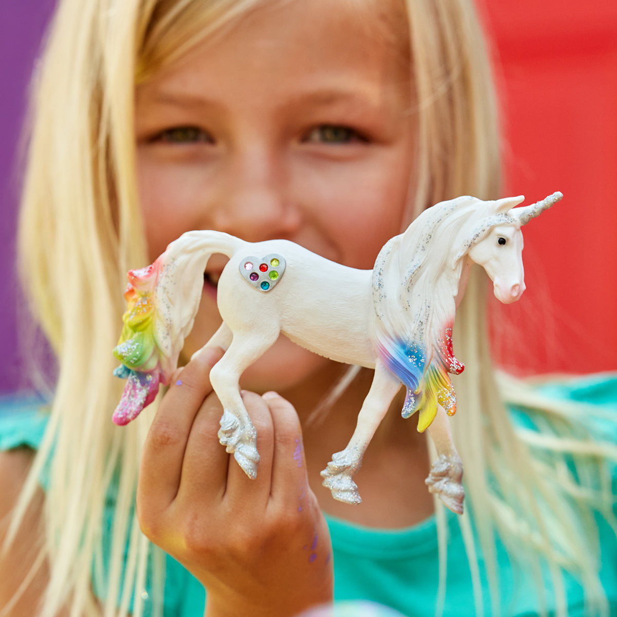 Ein junges Mädchen hält ein weißes Einhorn-Spielzeug mit Regenbogenmähne und -schwanz.