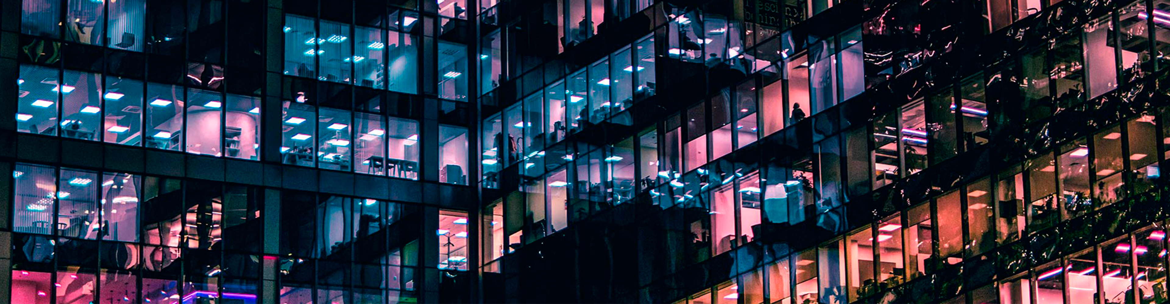 Nocny widok budynku z wieloma podświetlonymi oknami, biurami.