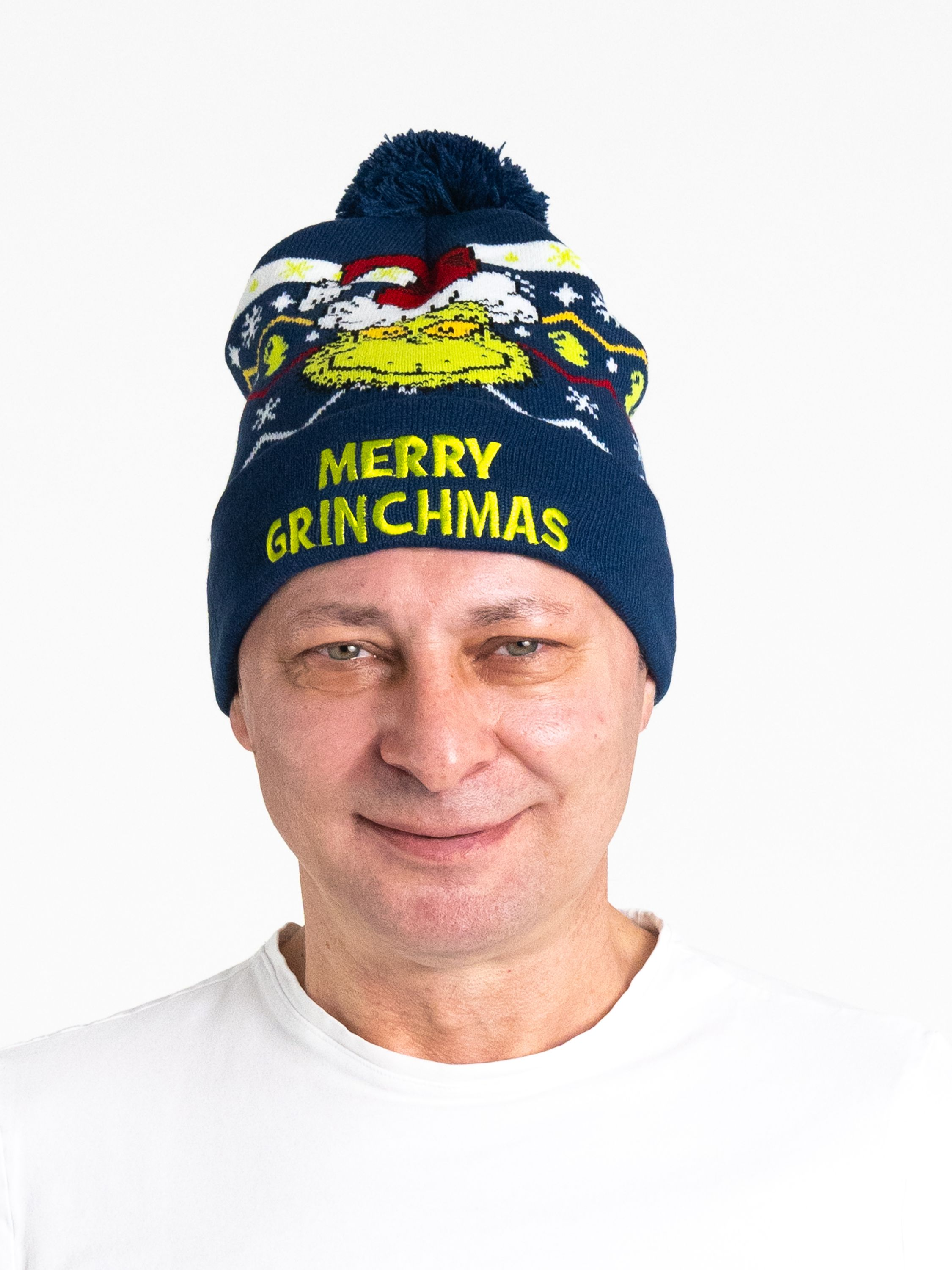 Ein Mann in einem weißen Hemd trägt eine blaue Mütze mit Grinch-Design.