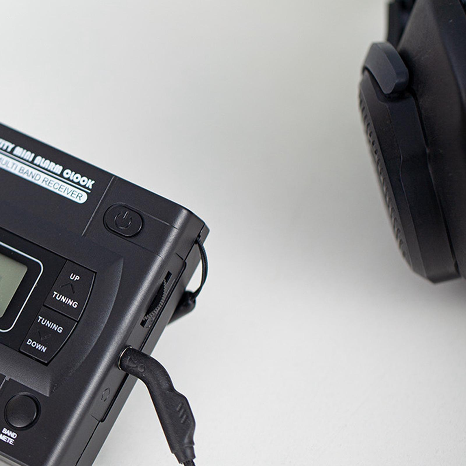 Nahaufnahme eines schwarzen Radios mit Kopfhöreranschluss und Kopfhörern vor weißem Hintergrund.