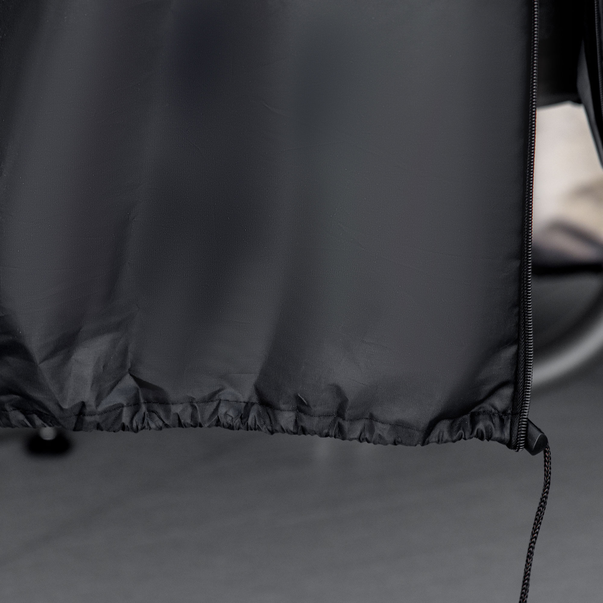 Schwarzes Tuch mit Kordelzug. Das Tuch ist zerknittert. Der Hintergrund ist grau.