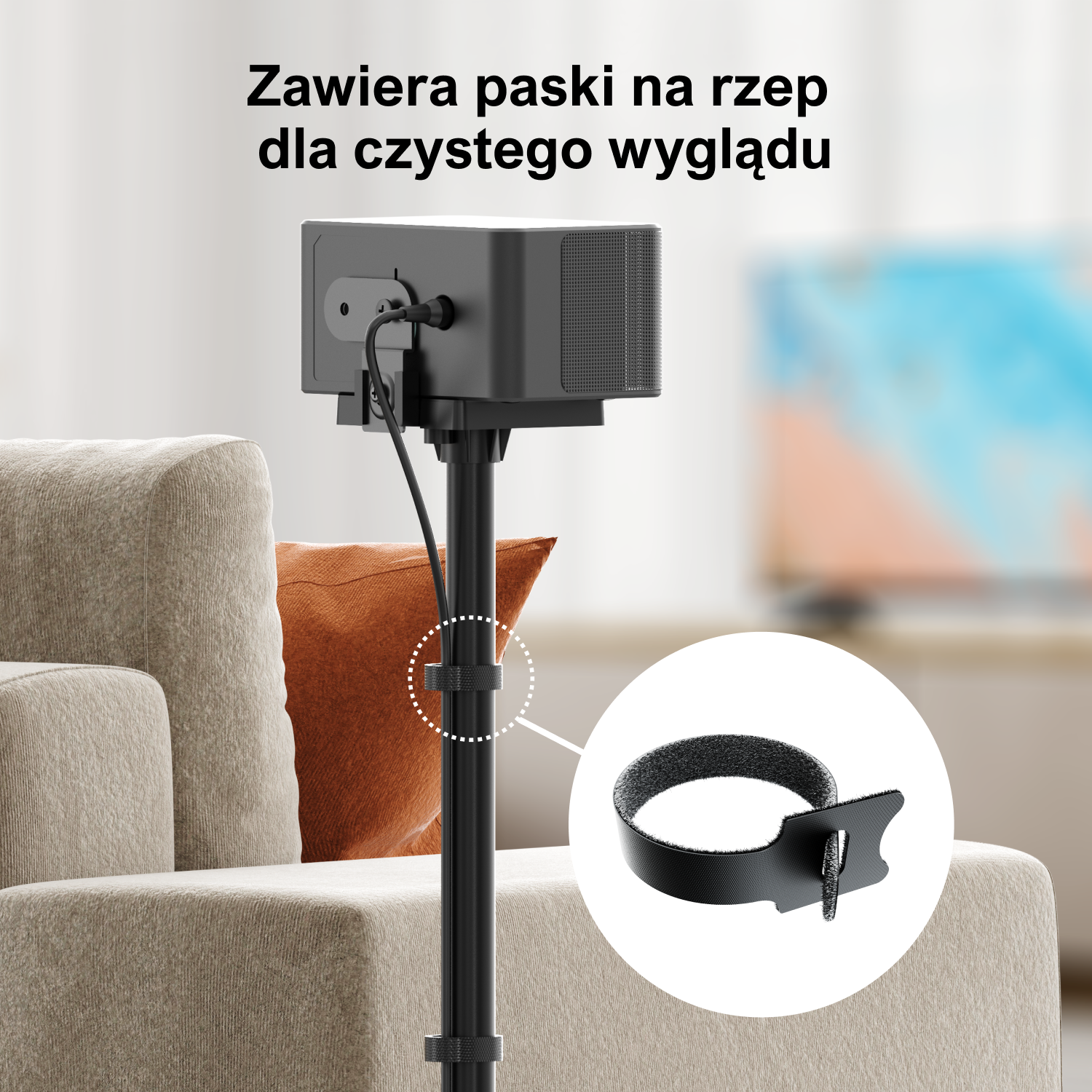 Czarny głośnik na stojaku z kablami, czarnym paskiem na rzep i w salonie.