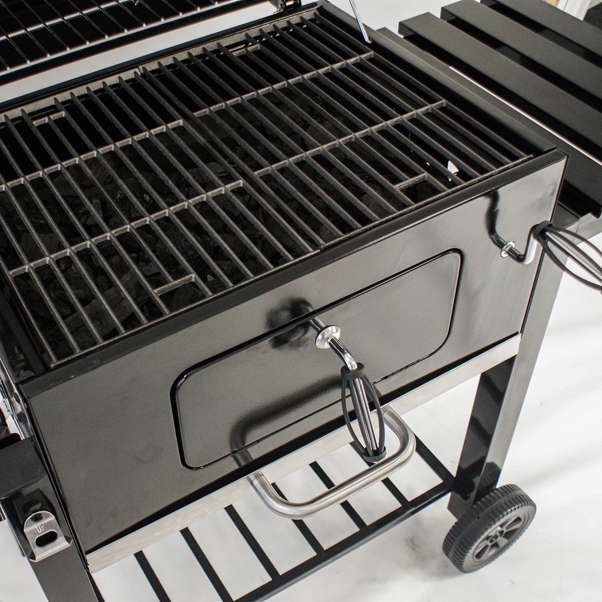 Schwarzer Holzkohlegrill mit Vordertür, Griff und Rost.