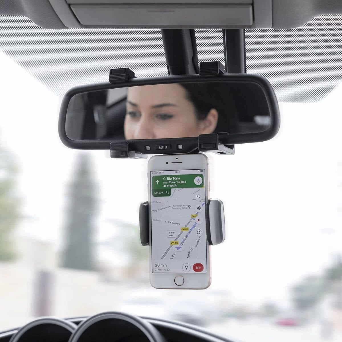 Un telefono in un supporto per auto, con il riflesso di una donna nello specchietto retrovisore.