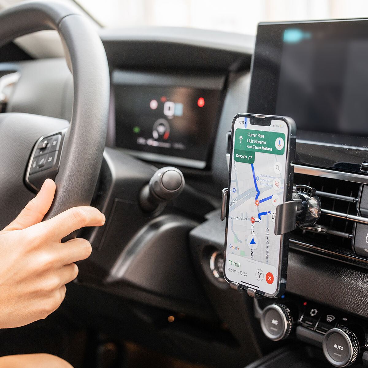 Mano sul volante, telefono con mappa nel supporto sul cruscotto.