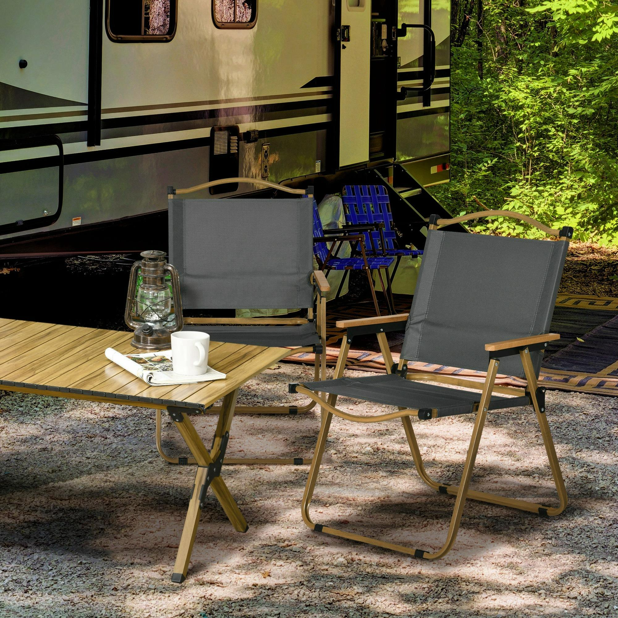 Zwei Klappstühle und ein Tisch im Freien mit Camping-Hintergrund.