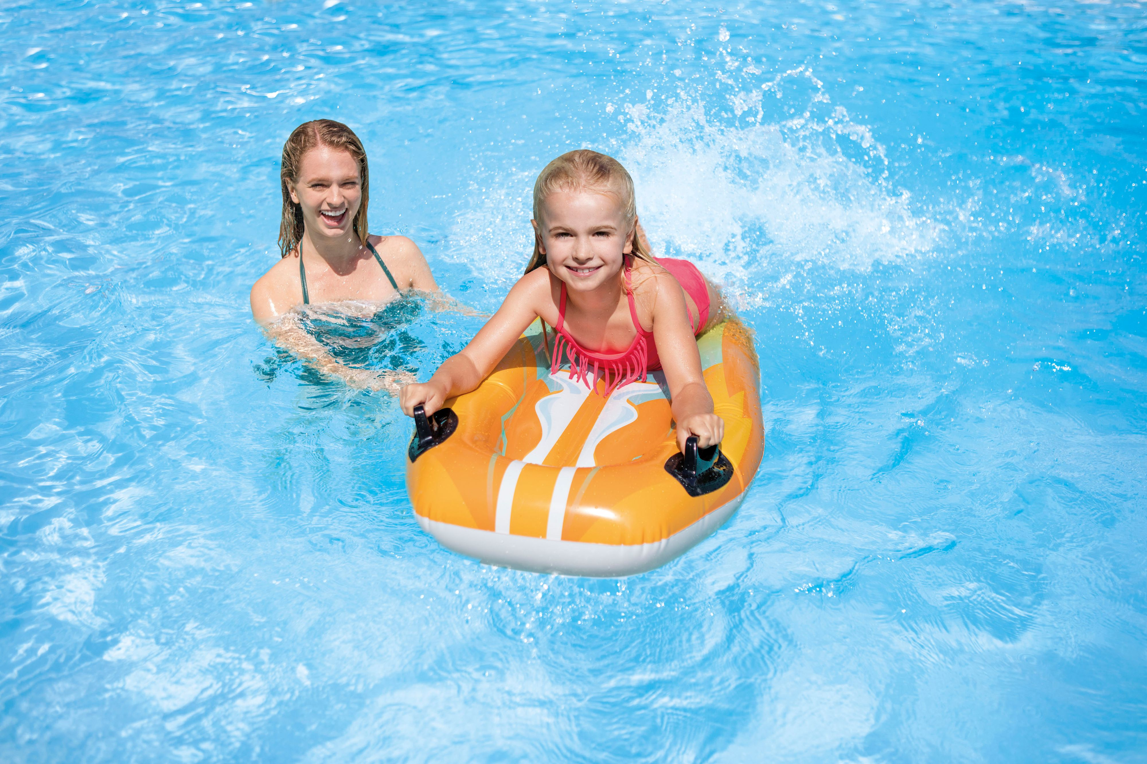 Frau und Mädchen auf einem aufblasbaren Wasserbrett in einem Pool.