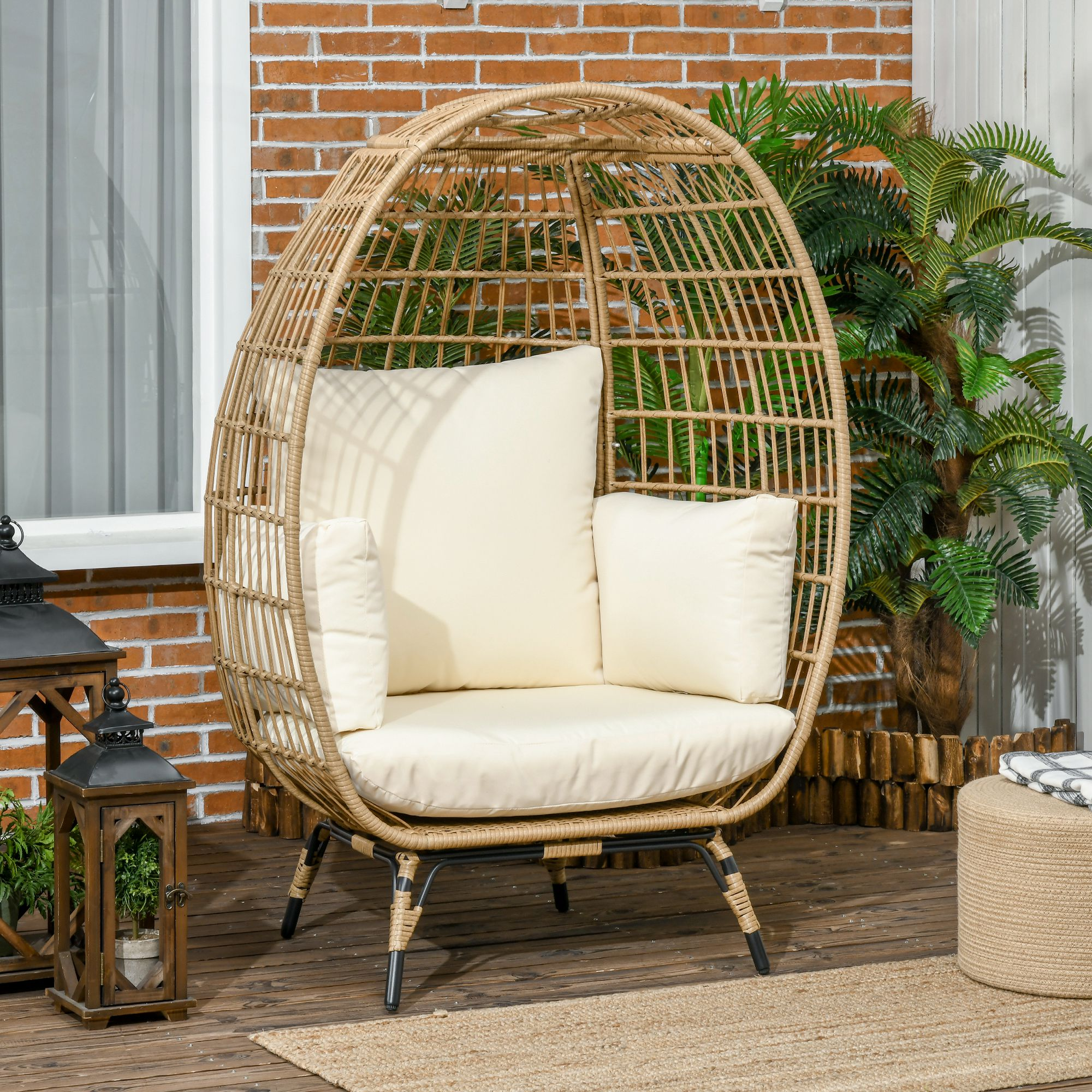 Rattan-Eiersessel auf einer Veranda mit Kissen. Pflanzen und Laternen im Hintergrund.
