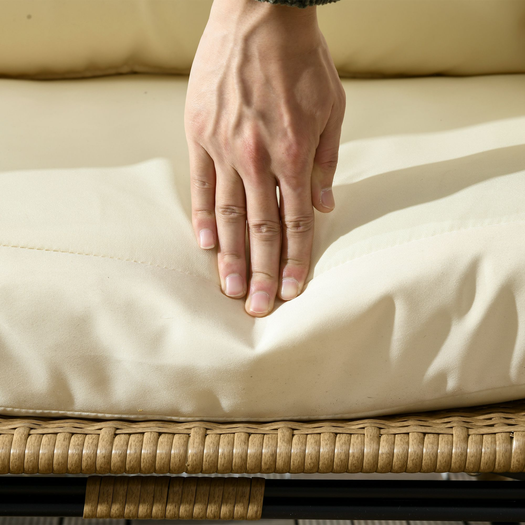 Hand drückt auf ein cremefarbenes Kissen eines Eier-Stuhls. Weidenstuhlrahmen.