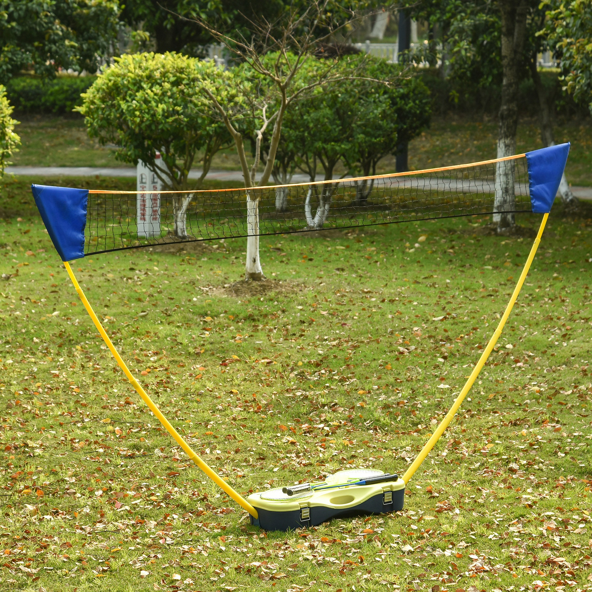 Ein Badmintonnetz auf Gras, mit gelben Pfosten, blauen Netzanfängen und einer Hülle mit Schlägern.